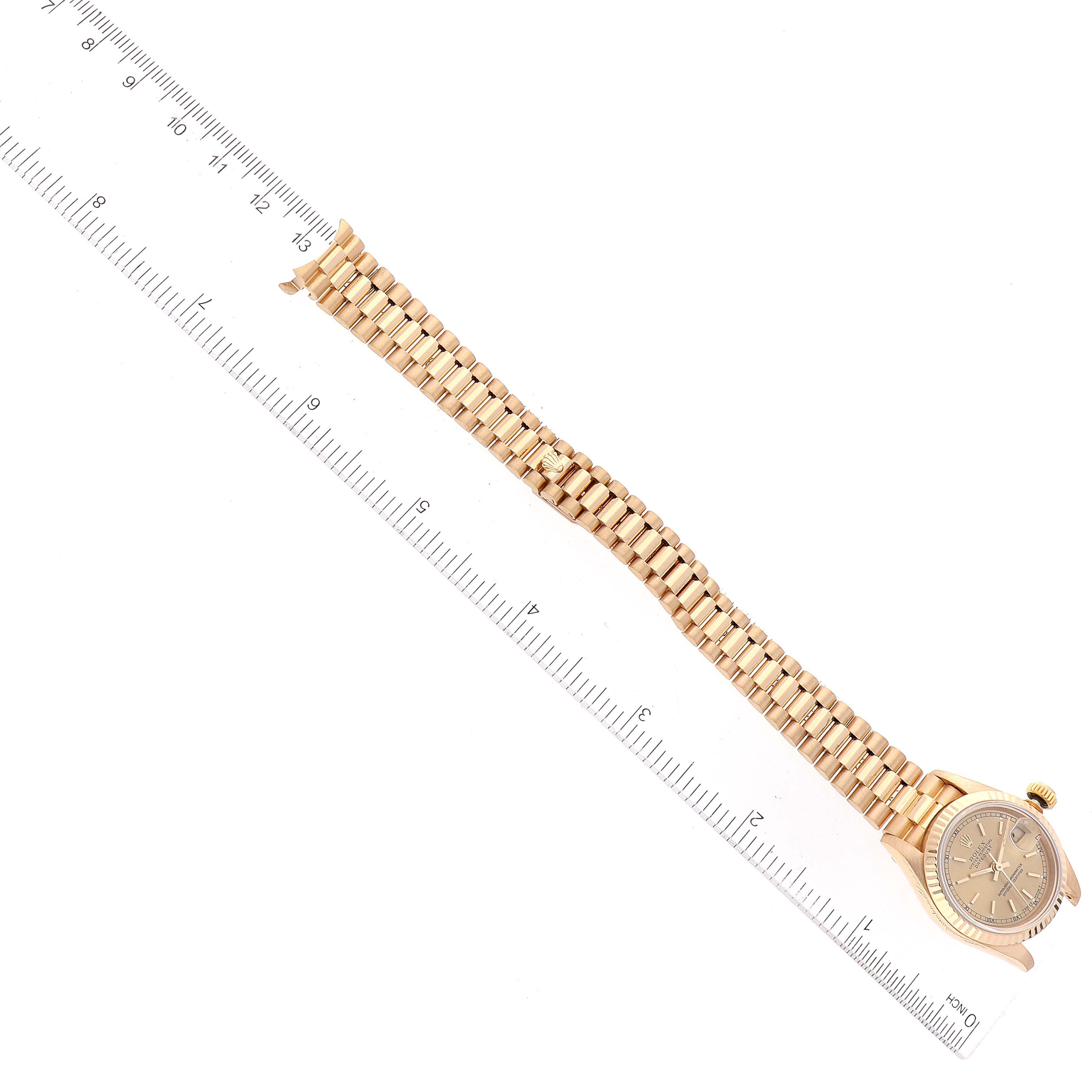 The image shows a Rolex President 69178 Women's Yellow Gold Champagne Dial 69178 Women's Yellow Gold Champagne Dial model watch laid flat next to a ruler, displaying the face and the entire band.