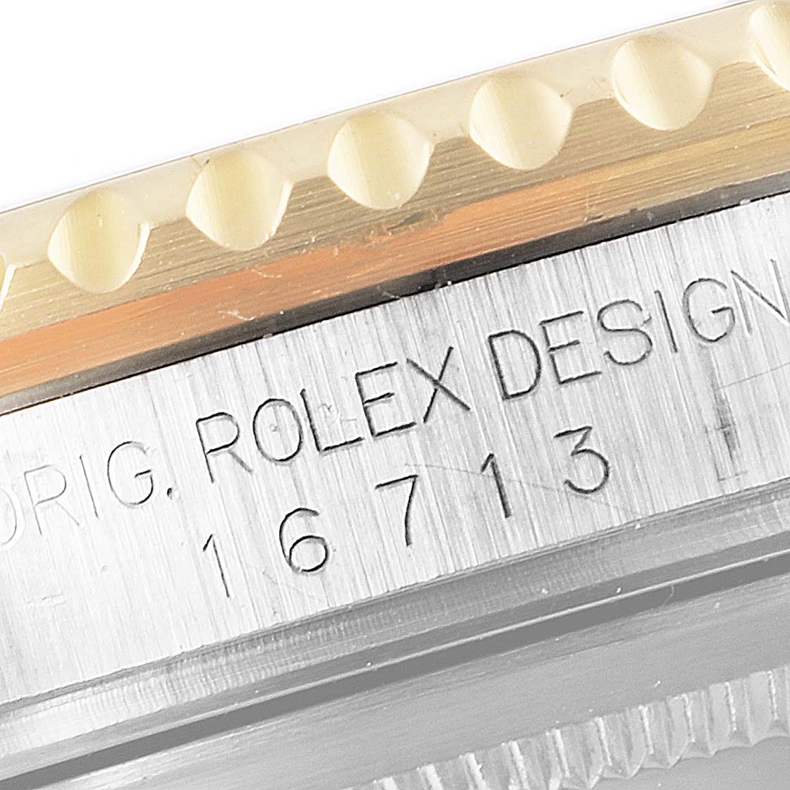 The image shows a close-up of the side of a Rolex GMT-Master 16713 Men's Steel and Gold (two tone) Champagne Dial 16713 Men's Steel and Gold (two tone) Champagne Dial watch, highlighting the engraved model number and part of the bezel.