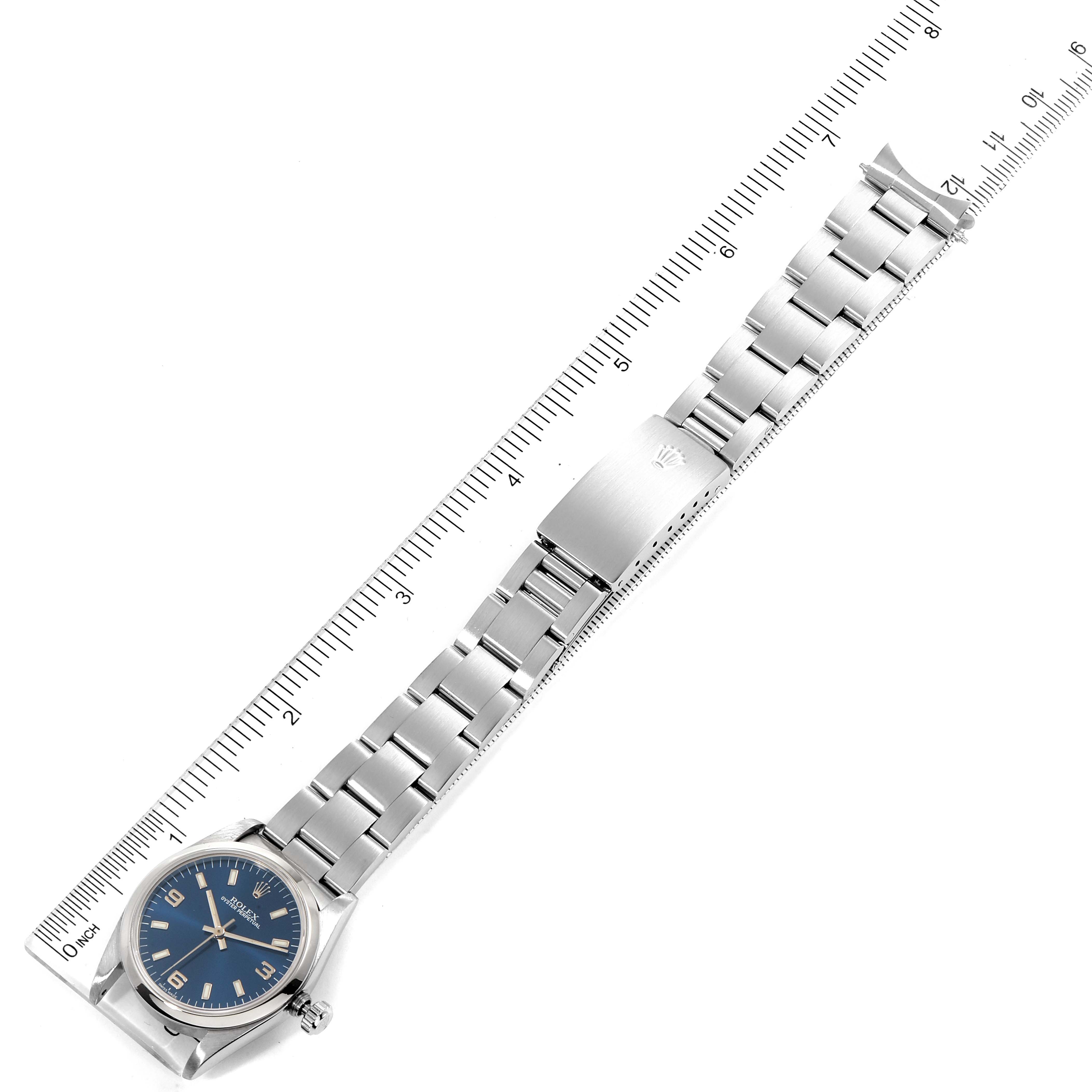 The image shows a Rolex Mid-Size 67480 Women
s Stainless Steel Blue Dial 67480 Women
s Stainless Steel Blue Dial watch laid flat with an open bracelet and a ruler for scale.