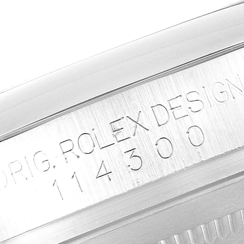 This image shows a close-up of the side case engraving of a Rolex Oyster Perpetual 114300 Men's Stainless Steel Silver Dial 114300 Men's Stainless Steel Silver Dial watch, detailing "ORIG. ROLEX DESIGN" and the model number "114300".