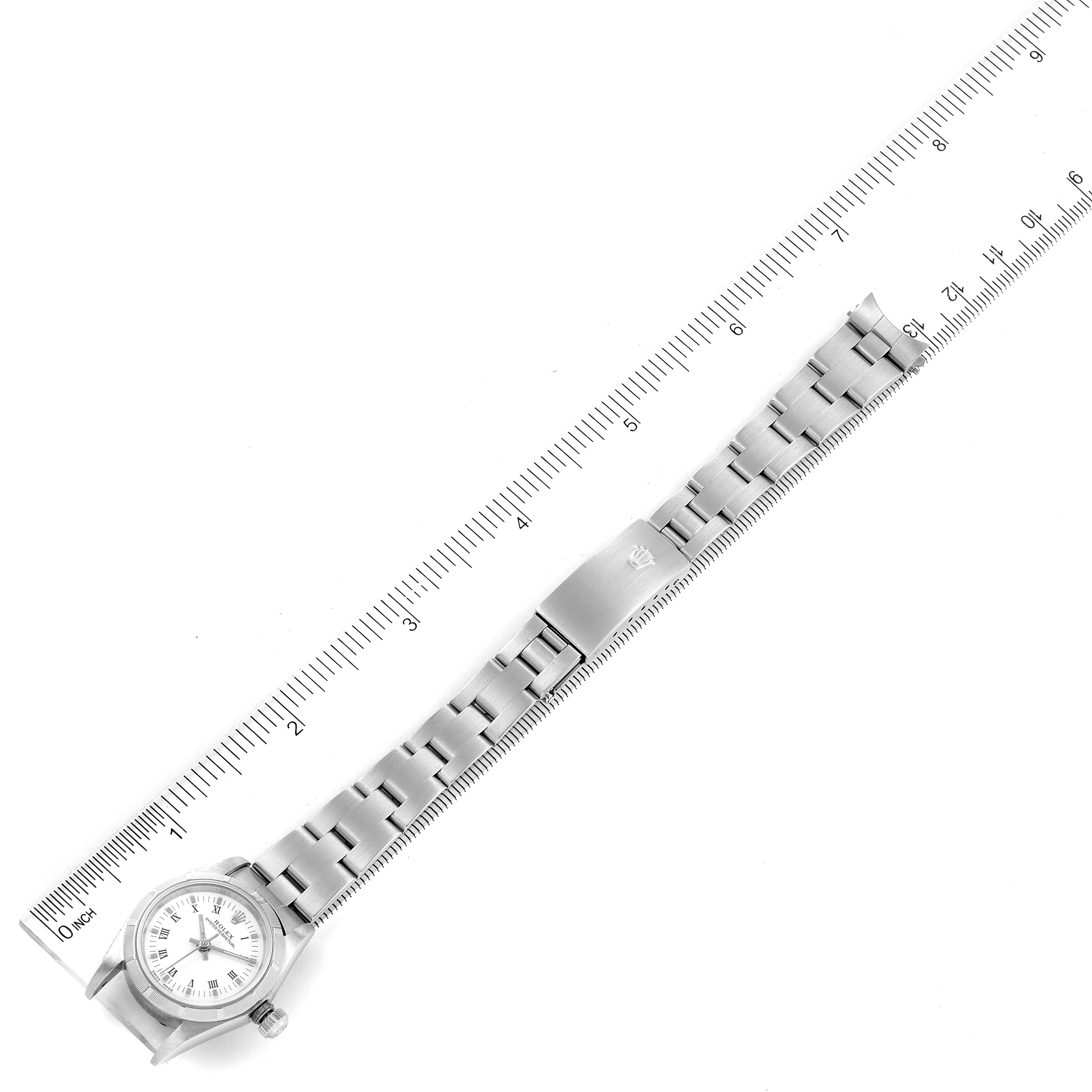 This image shows a top-down view of a Rolex Oyster Perpetual 76030 Women
s Stainless Steel White Dial 76030 Women
s Stainless Steel White Dial watch alongside a ruler, displaying the bracelet and watch face.
