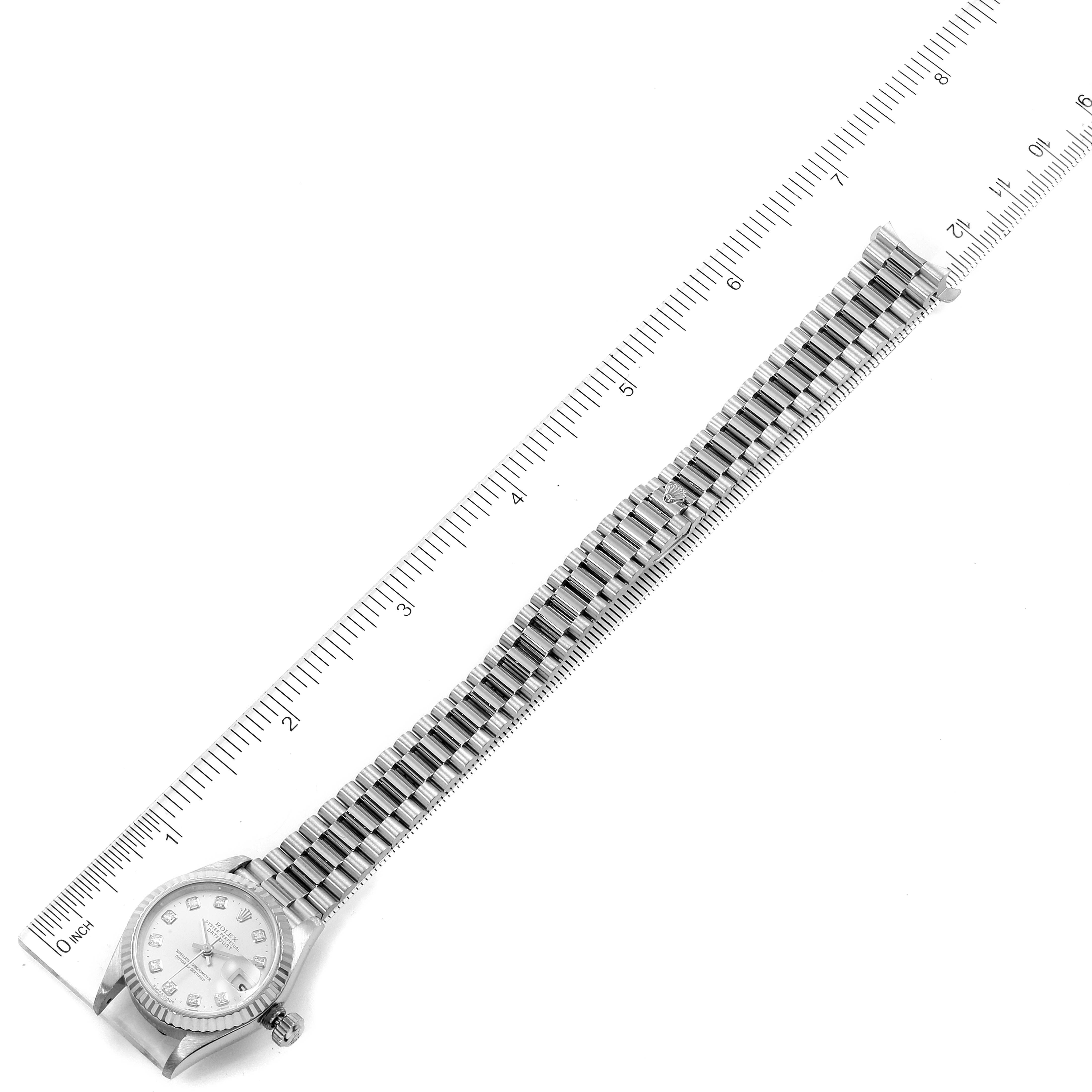 This top-down image shows a Rolex President 79179 Women's White Gold Silver Dial 79179 Women's White Gold Silver Dial model watch, including its face, bracelet, and ruler for scale.