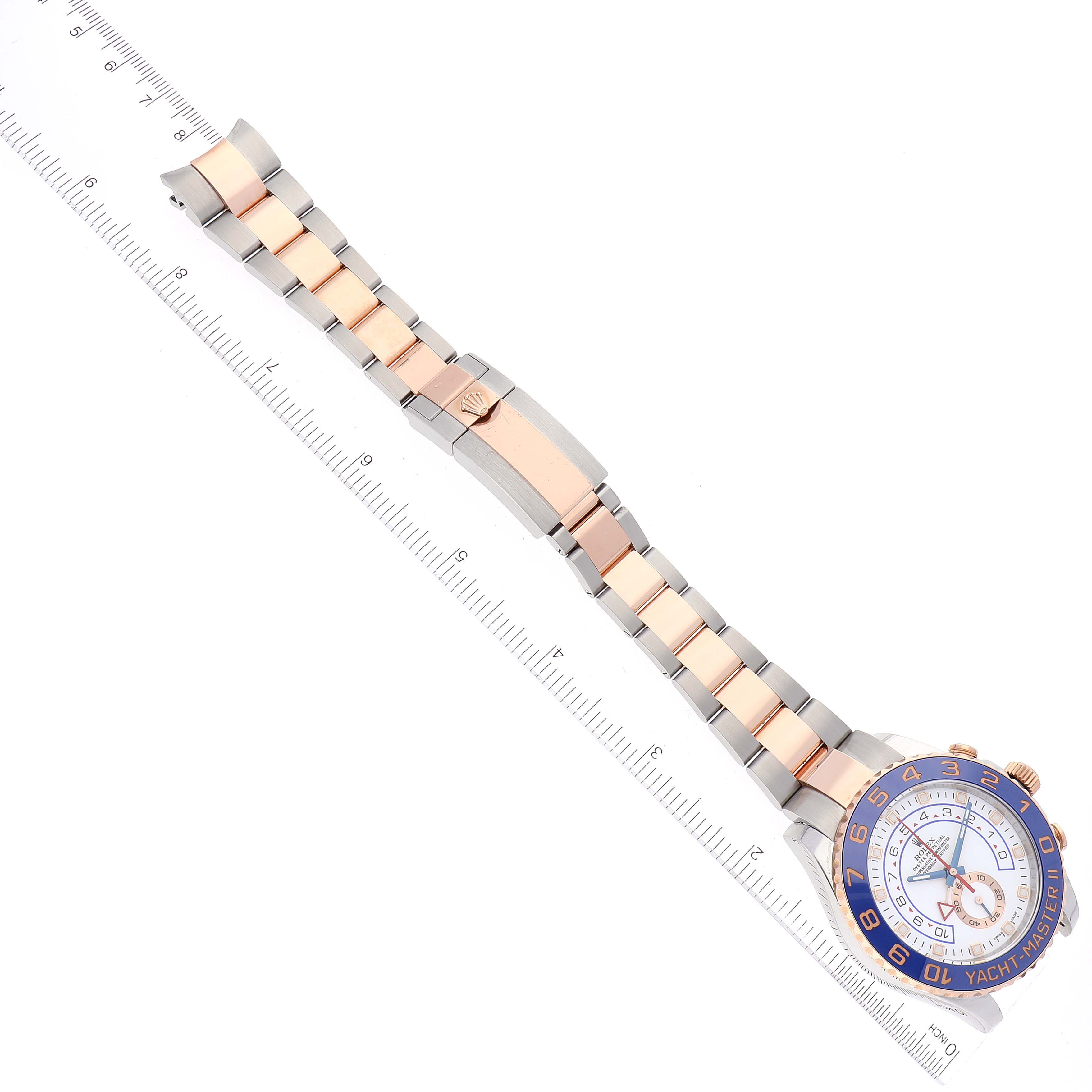 The Rolex Yacht-Master 116681 Men's Steel and Gold (two tone) White Dial 116681 Men's Steel and Gold (two tone) White Dial watch is shown laid flat with its strap extended alongside a ruler.
