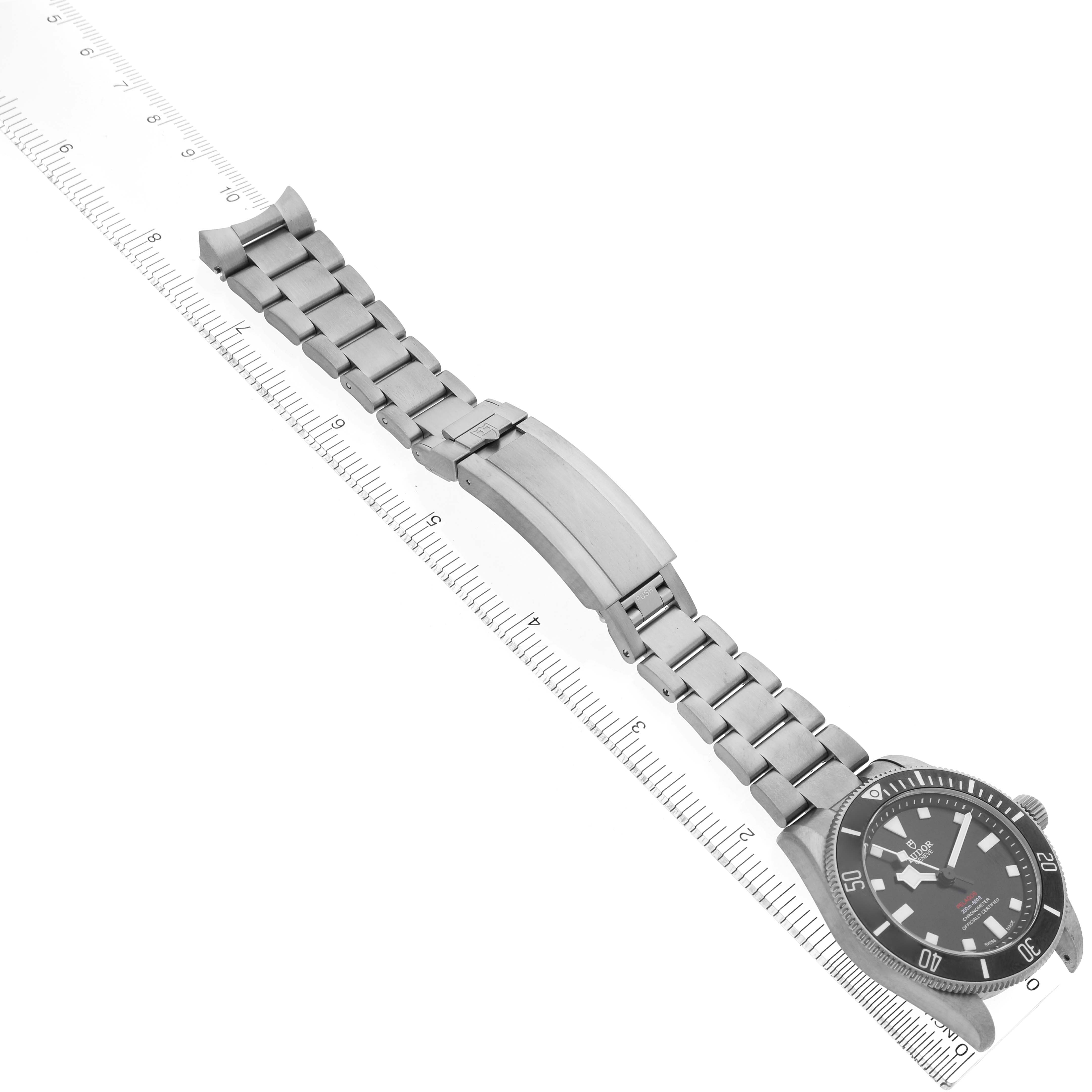 The Tudor Pelagos 25407 Men's Titanium Black Dial watch is shown from a top-down angle, displaying the face, bracelet, and clasp aligned with a ruler.
