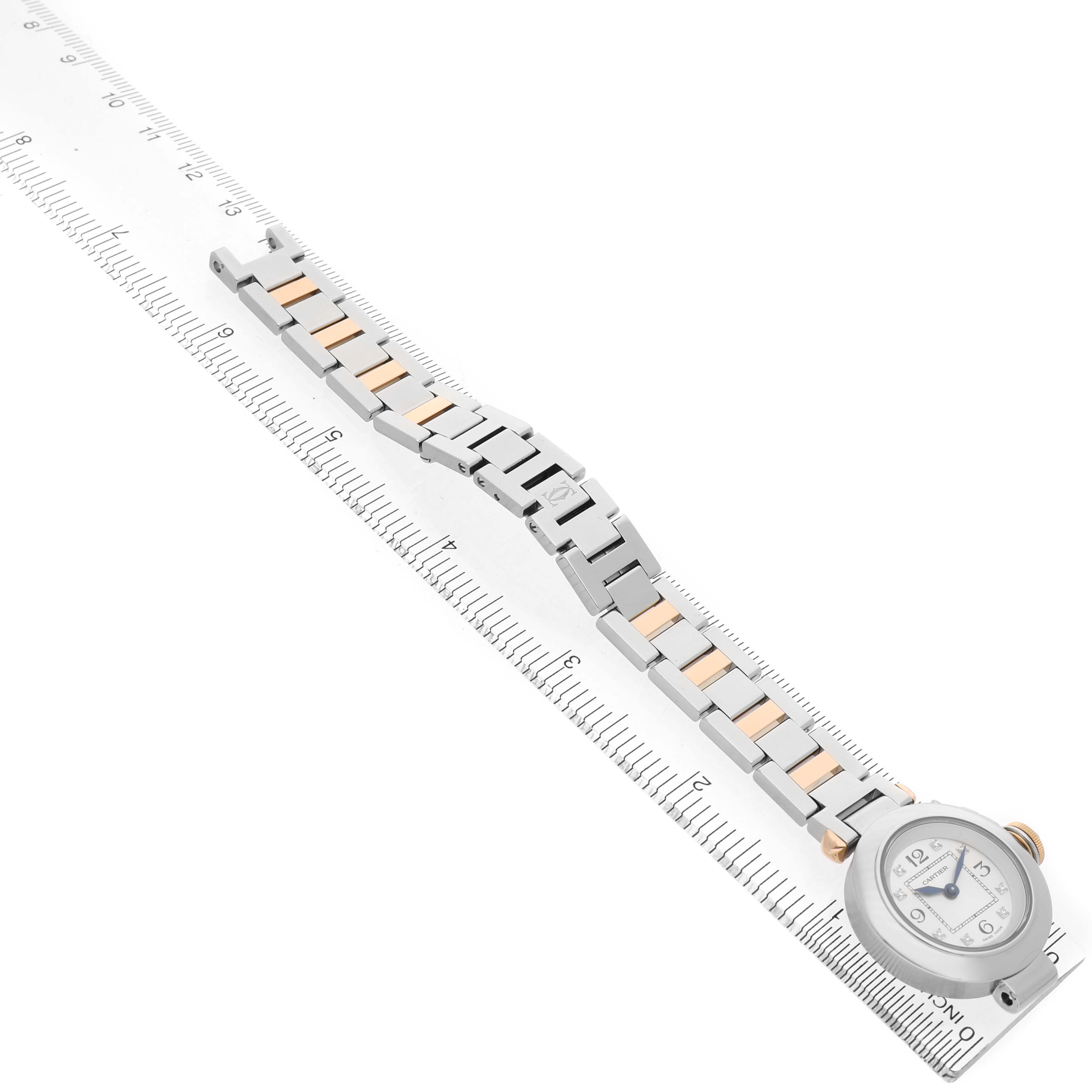 The Cartier Pasha WJ124020 Women's Steel and Gold (two tone) Silver Dial watch is shown diagonally, highlighting the face, bracelet, and clasp, with a ruler underneath.