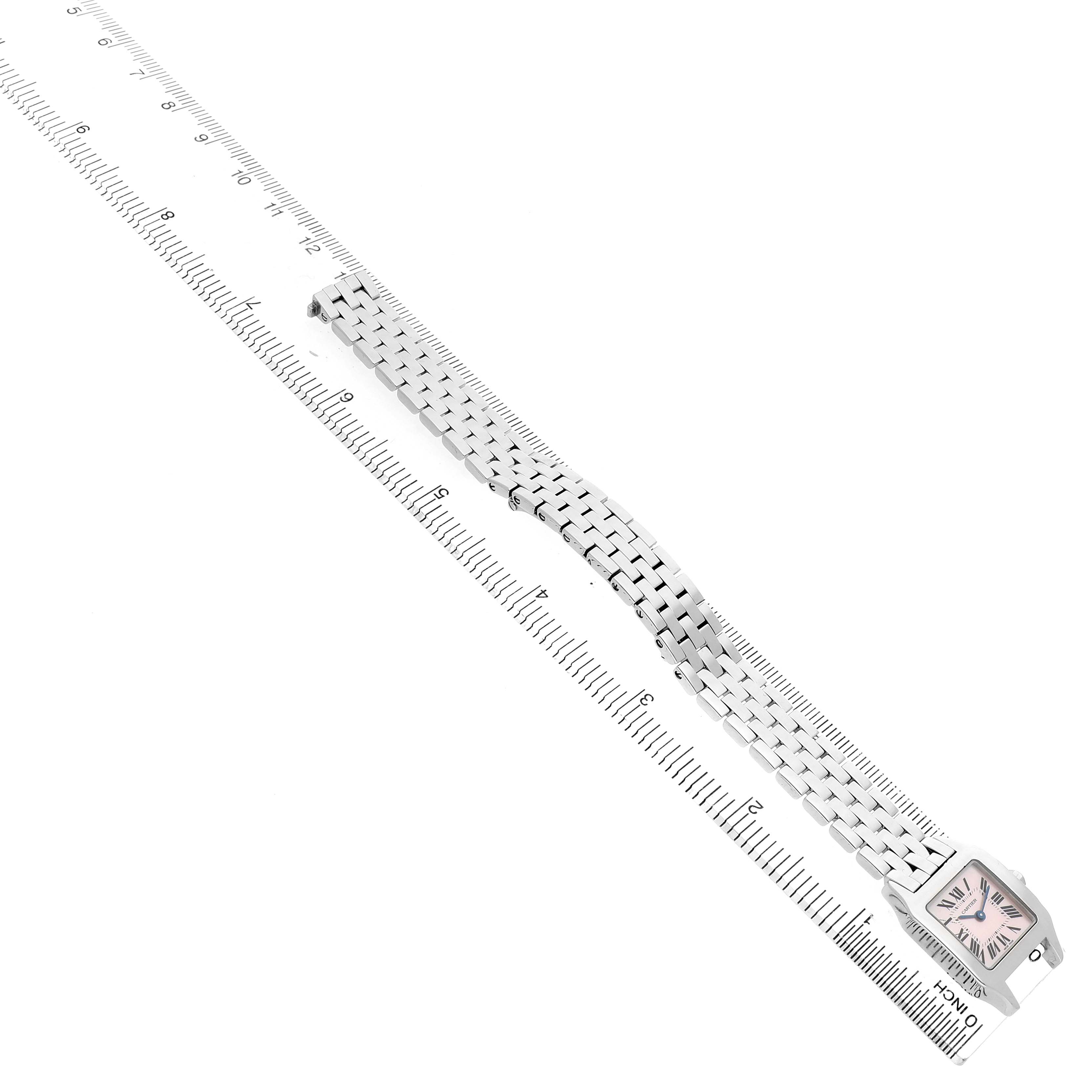 The Cartier Santos Demoiselle W25075Z5 Women's Stainless Steel Mother of Pearl Dial watch is shown at an angle displaying its face and linked bracelet, positioned diagonally along a ruler.