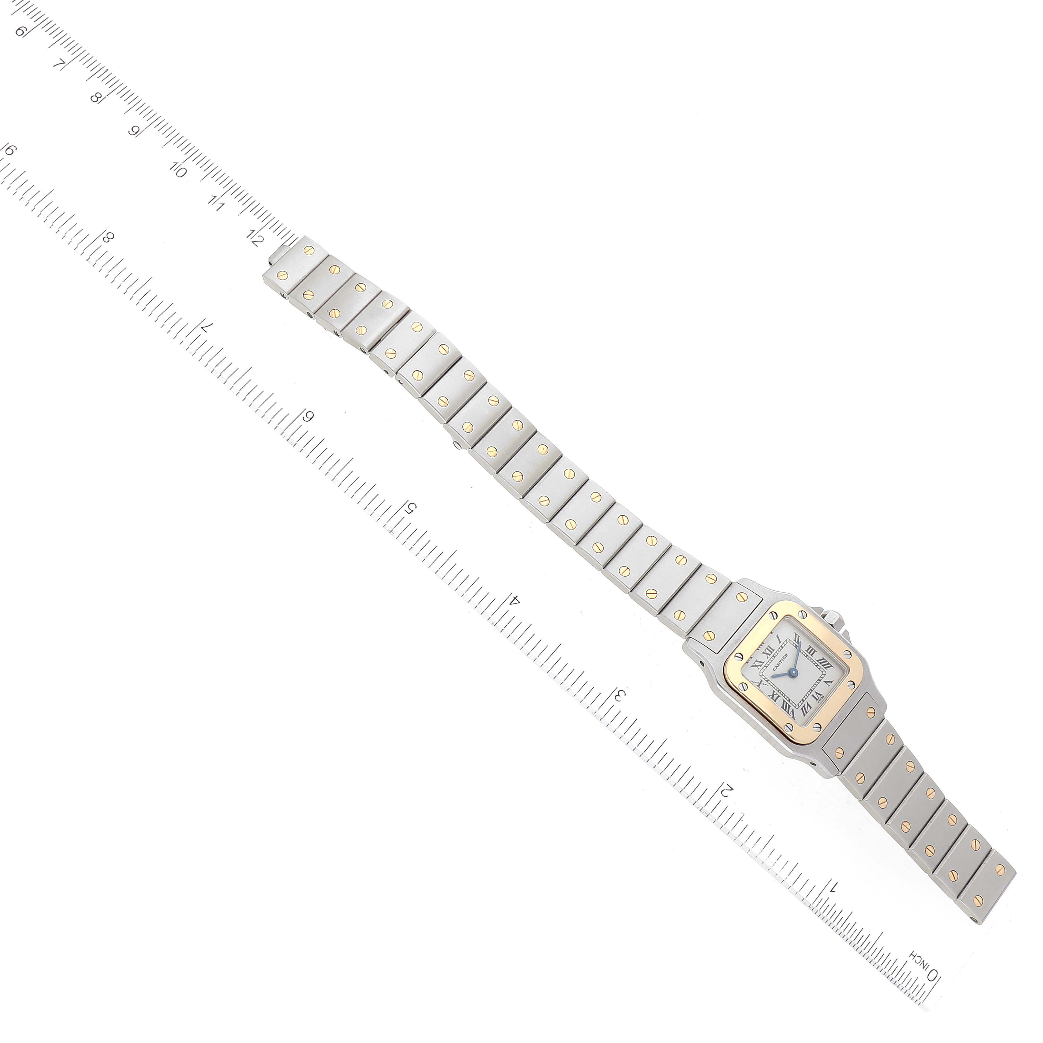 The Cartier Santos W20012C4 Women's Steel and Gold (two tone) Silver Dial W20012C4 Women's Steel and Gold (two tone) Silver Dial watch is shown from a top-down angle, displaying the entire band and face, with a ruler for measurement.