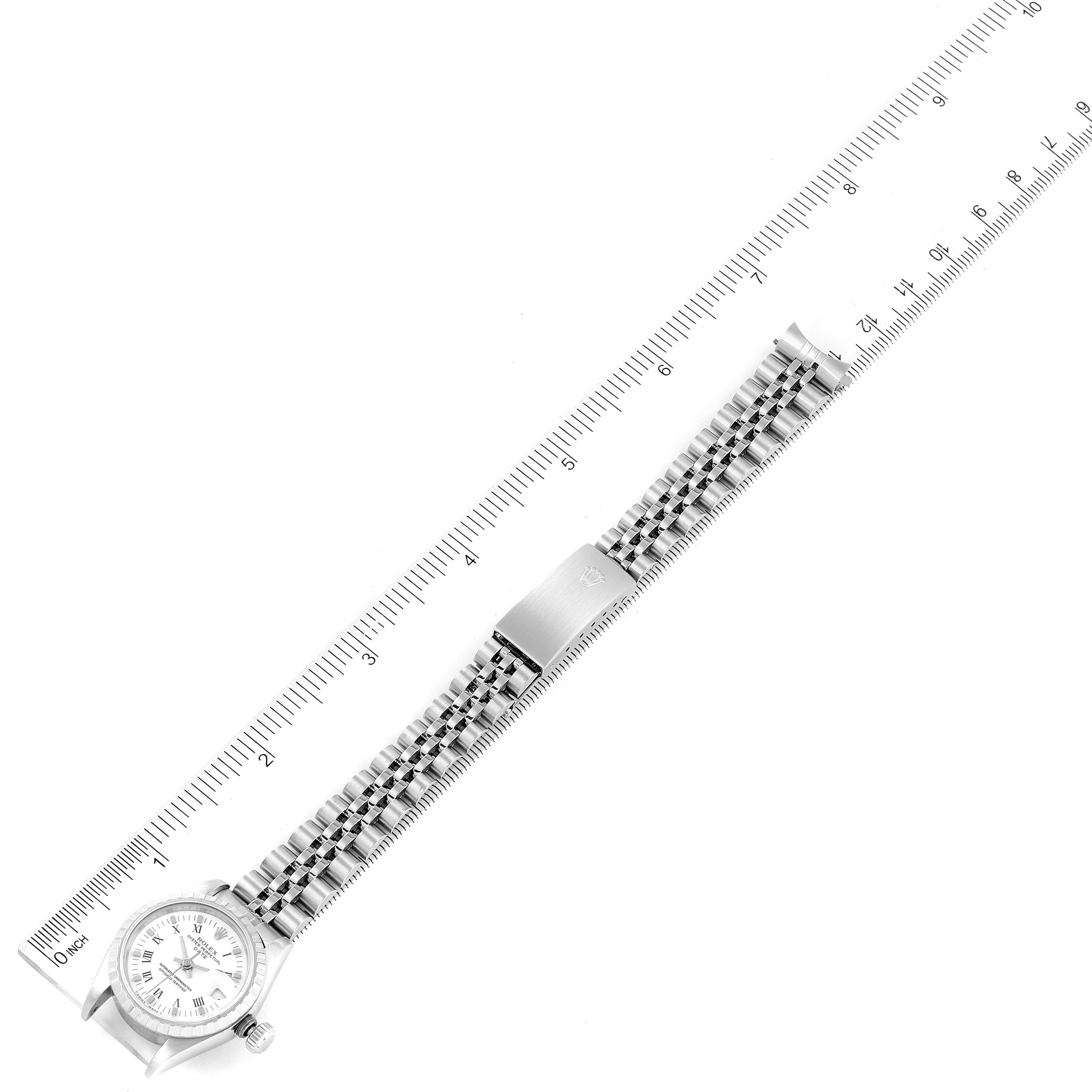 The image shows a top view of a Rolex Date 69240 Women's Stainless Steel White Dial 69240 Women's Stainless Steel White Dial model watch, including the face, bezel, band, and clasp, alongside a ruler for scale.