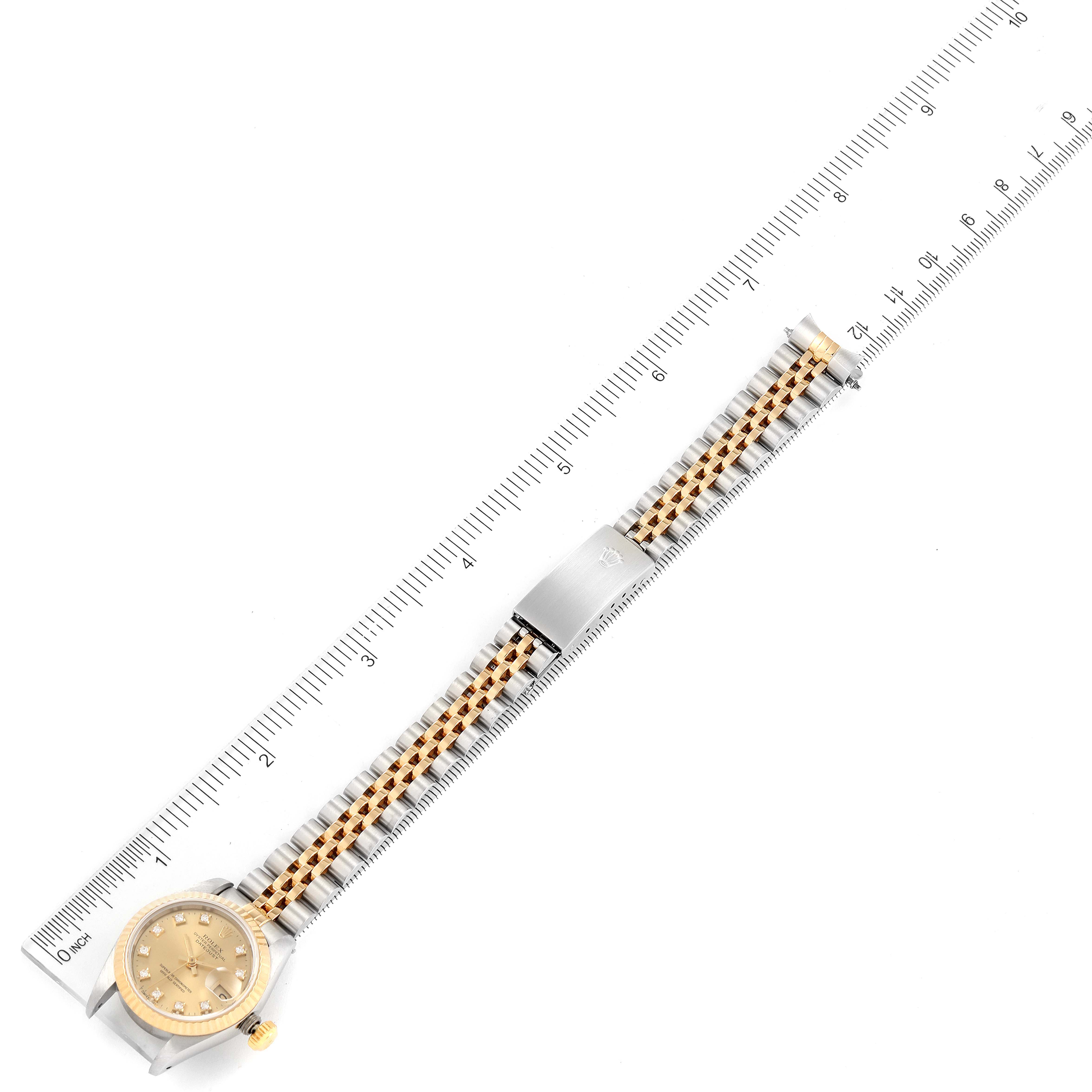The image shows a full-length, top-down view of a Rolex Datejust 69173 Women
s Steel and Gold (two tone) Champagne Dial 69173 Women
s Steel and Gold (two tone) Champagne Dial watch next to a ruler for scale.