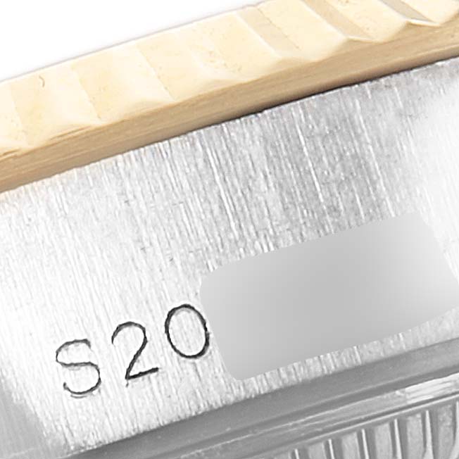 Close-up view of the watch case edge of a Rolex Datejust 69173 Women
s Steel and Gold (two tone) Champagne Dial 69173 Women
s Steel and Gold (two tone) Champagne Dial showing engraved serial numbers and part of the bezel.