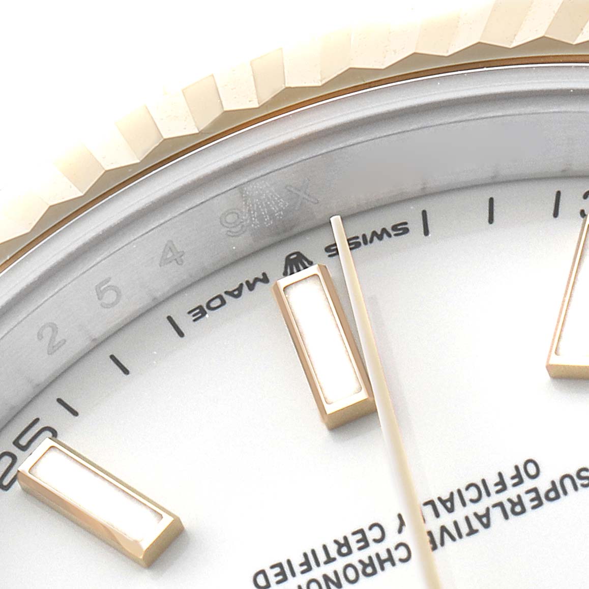 This macro shot of the Rolex Datejust 41 126333 Men's Steel and Gold (two tone) White Dial 126333 Men's Steel and Gold (two tone) White Dial watch shows part of the bezel, dial, and hour markers.