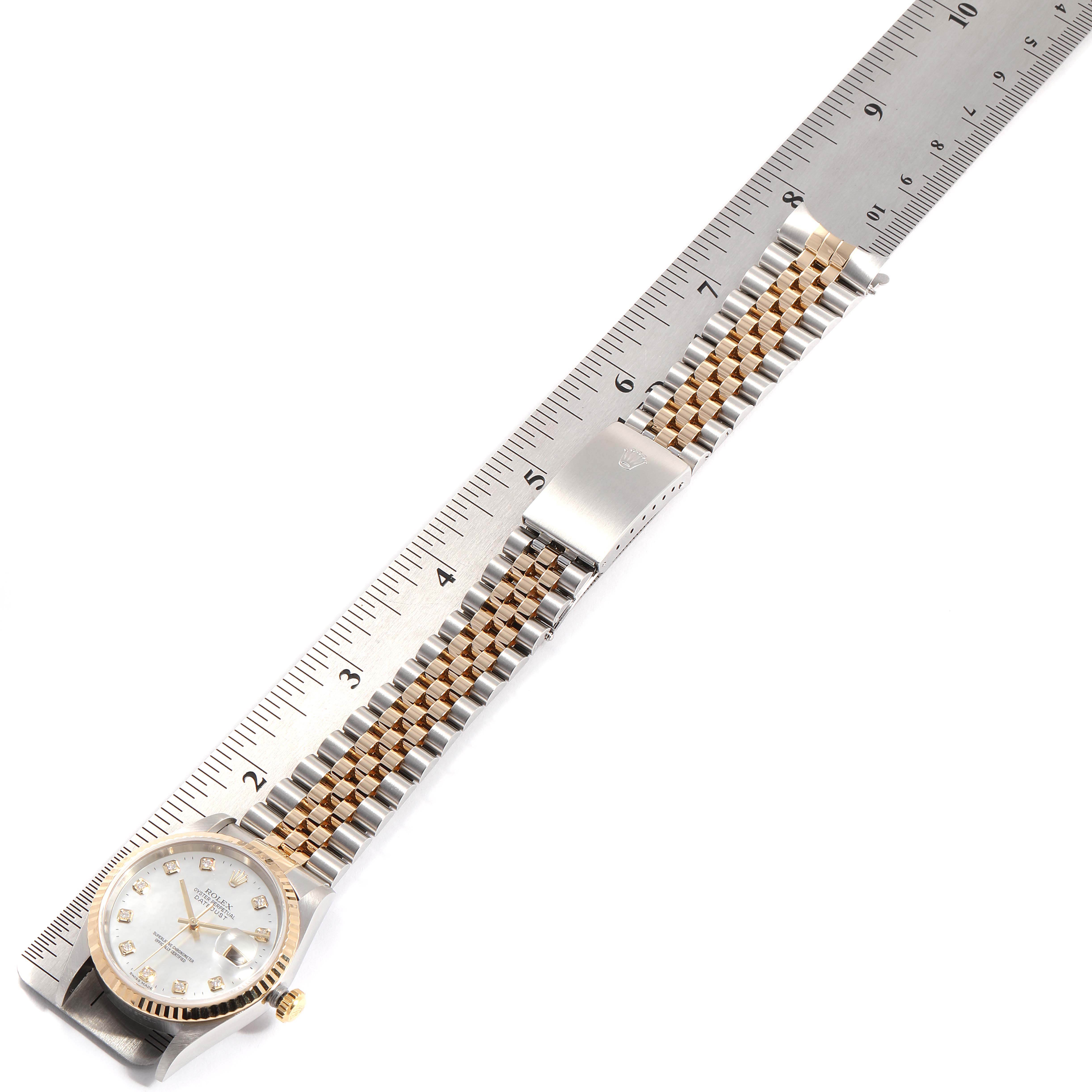 The Rolex Datejust 16233 Men
s Steel and Gold (two tone) Mother of Pearl Dial 16233 Men
s Steel and Gold (two tone) Mother of Pearl Dial watch is shown fully extended with a metal bracelet next to a ruler for scale.