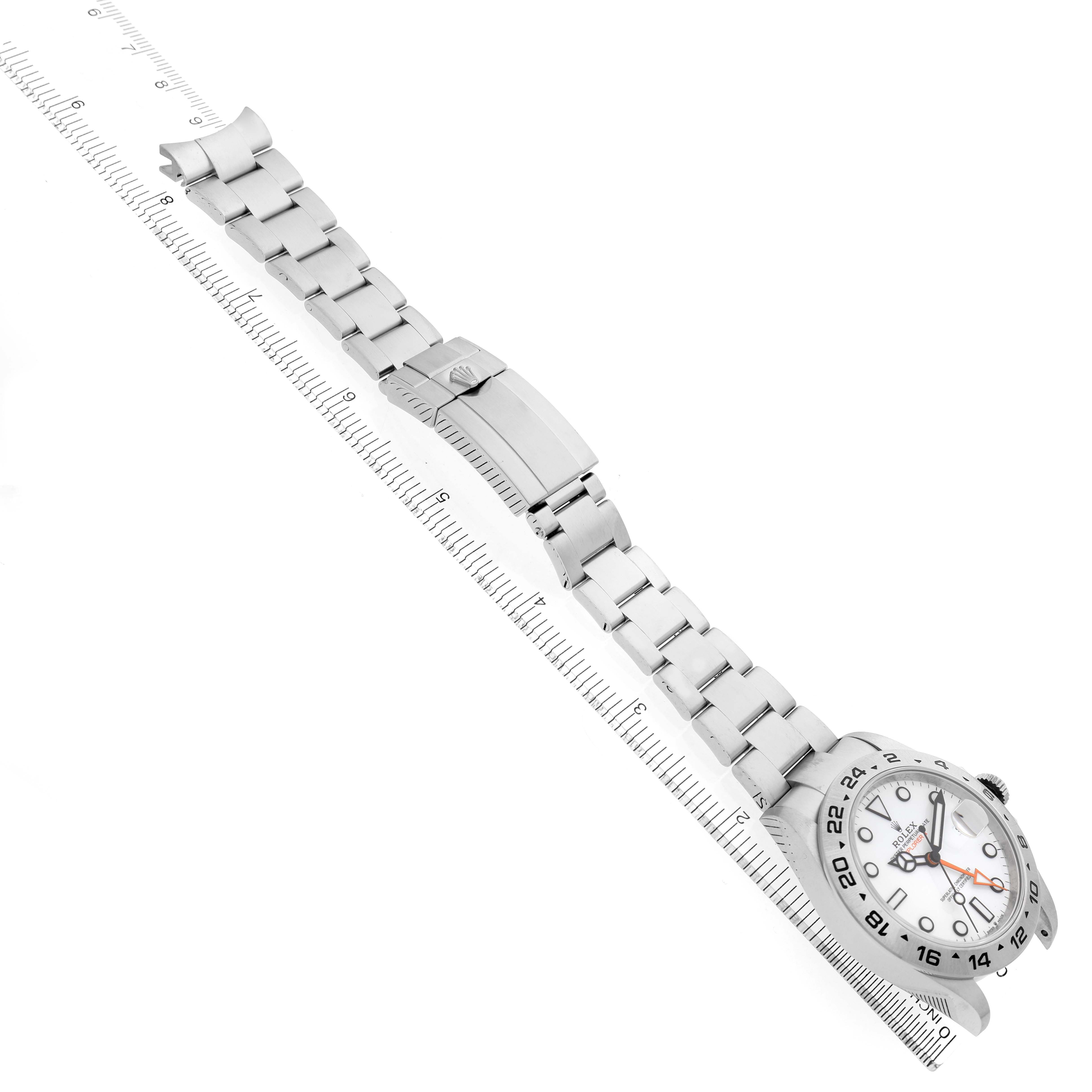 The Rolex Explorer 226570 Men's Stainless Steel White Dial watch is shown at an angle emphasizing the bracelet and clasp, alongside a ruler for scale.