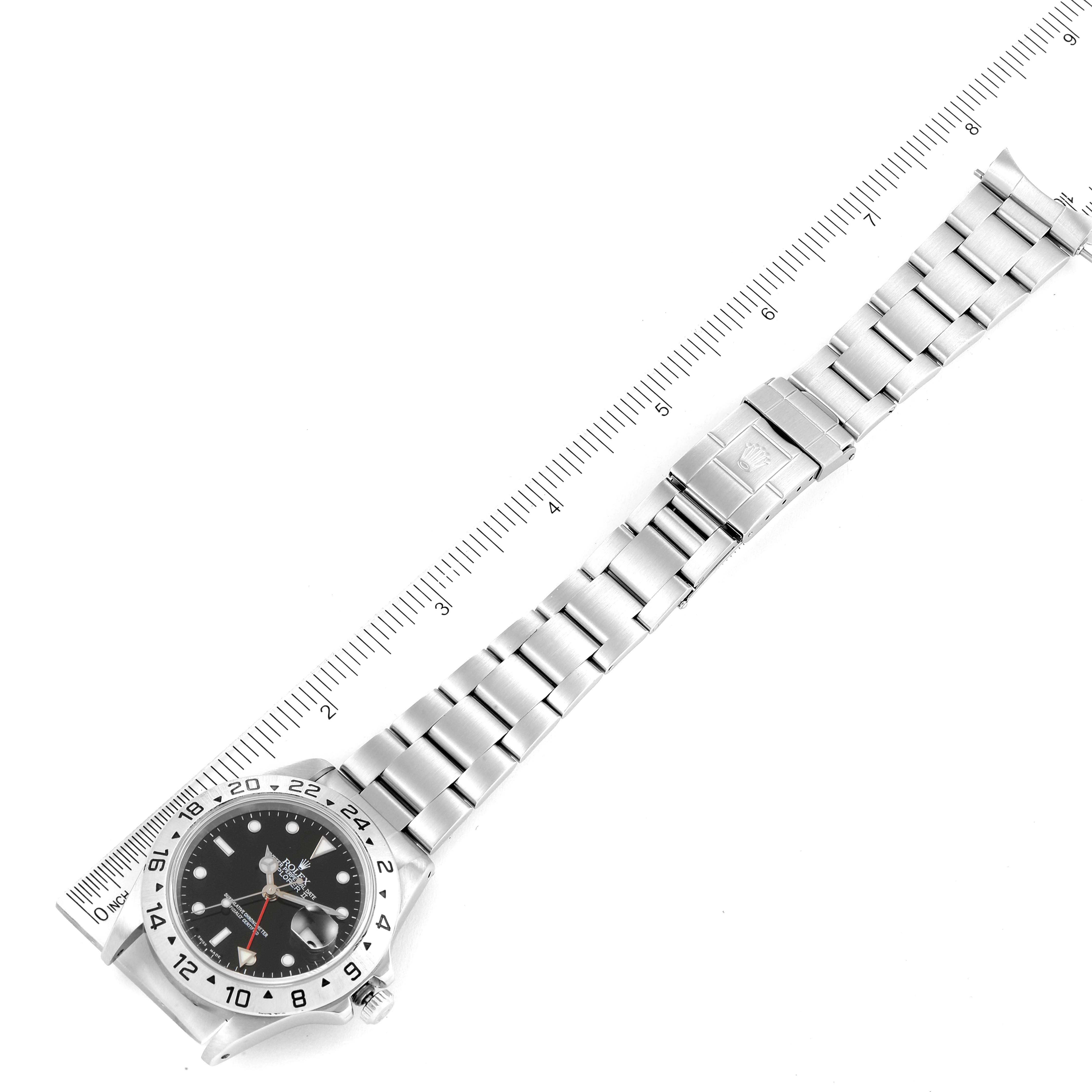 This image shows a top-down view of the Rolex Explorer 16570 Men
s Stainless Steel Black Dial 16570 Men
s Stainless Steel Black Dial watch with its dial, bezel, and full metal bracelet next to a ruler.