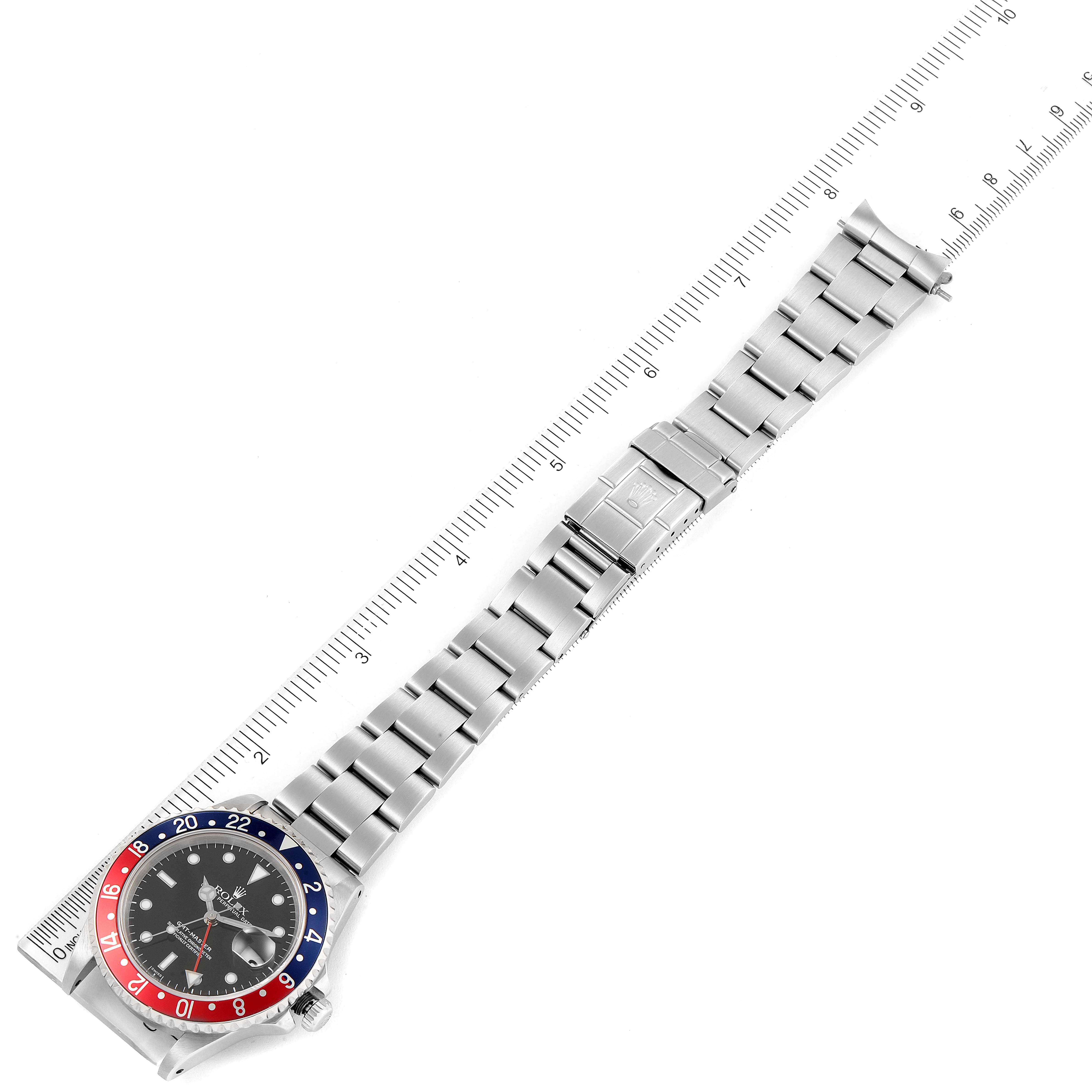 The image shows a top-down view of a Rolex GMT-Master 16700 Men
s Stainless Steel Black Dial 16700 Men
s Stainless Steel Black Dial watch, displaying the face, bezel, and full bracelet alongside a ruler for scale.
