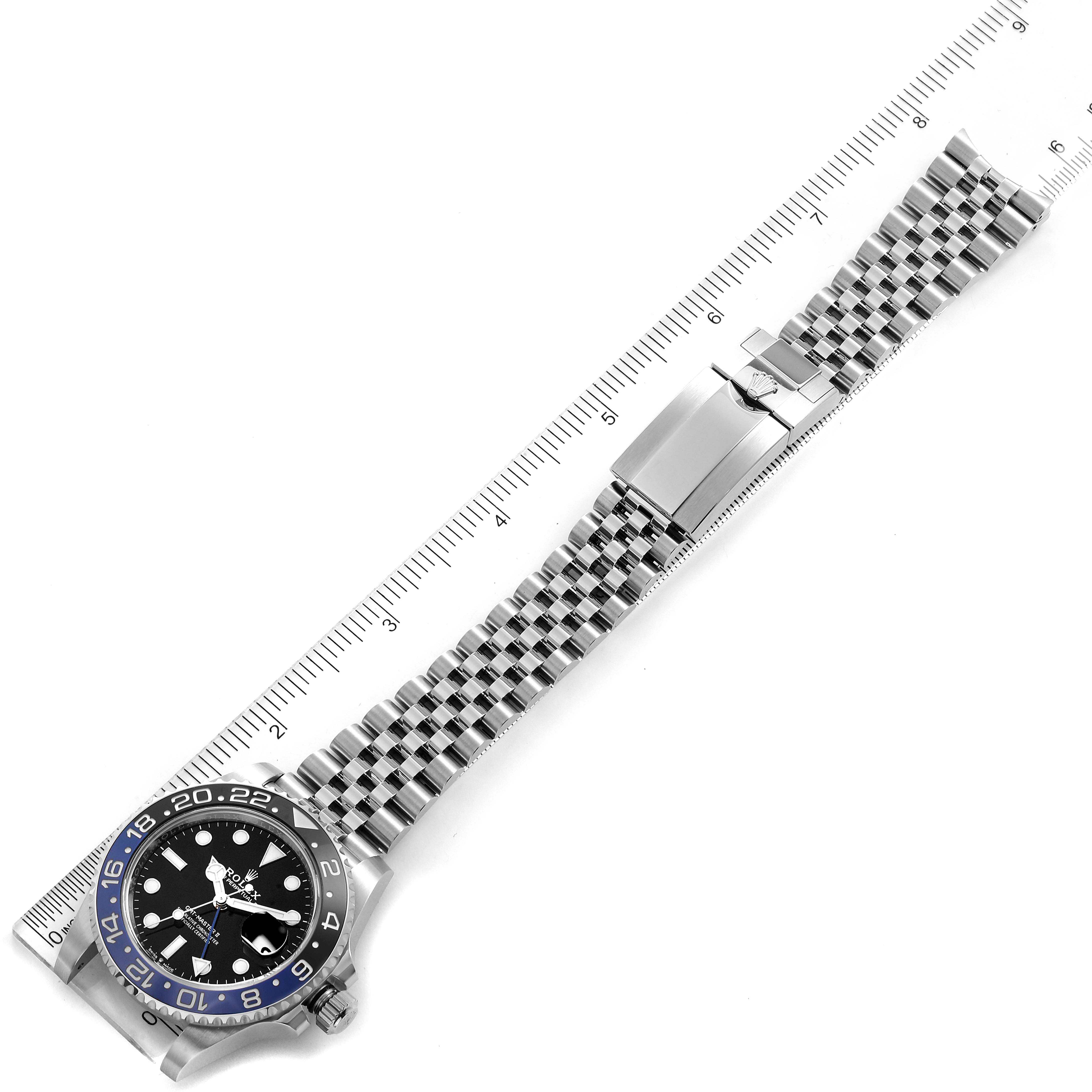 The image shows a top view of a Rolex GMT-Master 126710 Men
s Stainless Steel Black Dial 126710 Men
s Stainless Steel Black Dial watch along with a measuring ruler, displaying the watch face and entire metal bracelet.