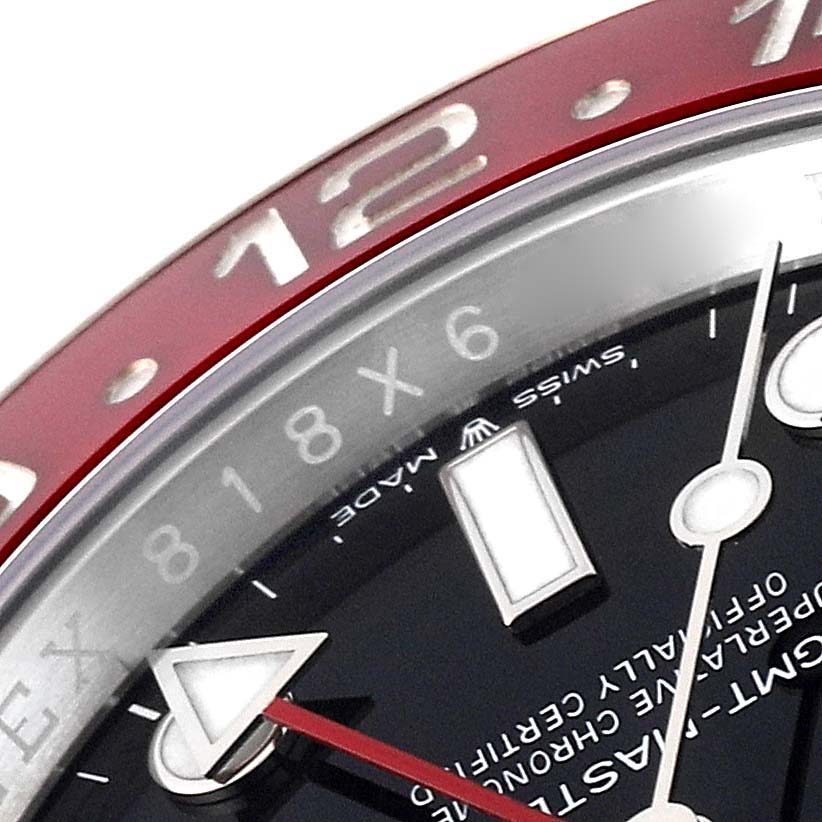 Close-up of the GMT-Master Rolex watch showing the red bezel, part of the dial, and hands.