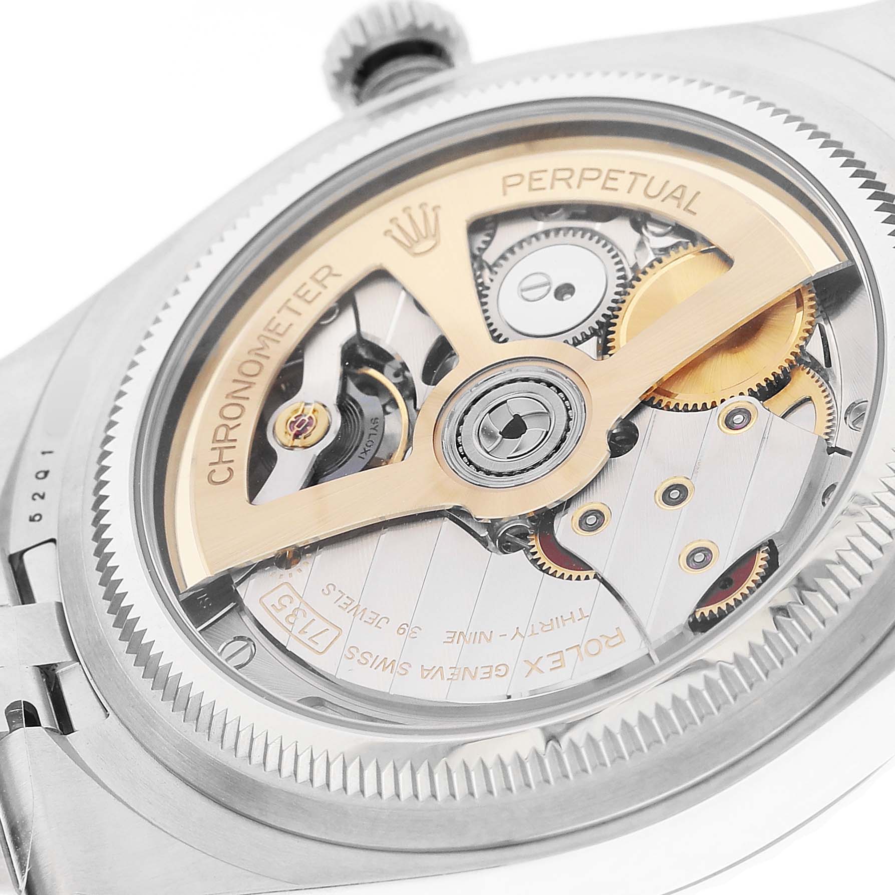 The image shows the back of the Rolex Land-Dweller, highlighting its intricate mechanical movement and rotor.