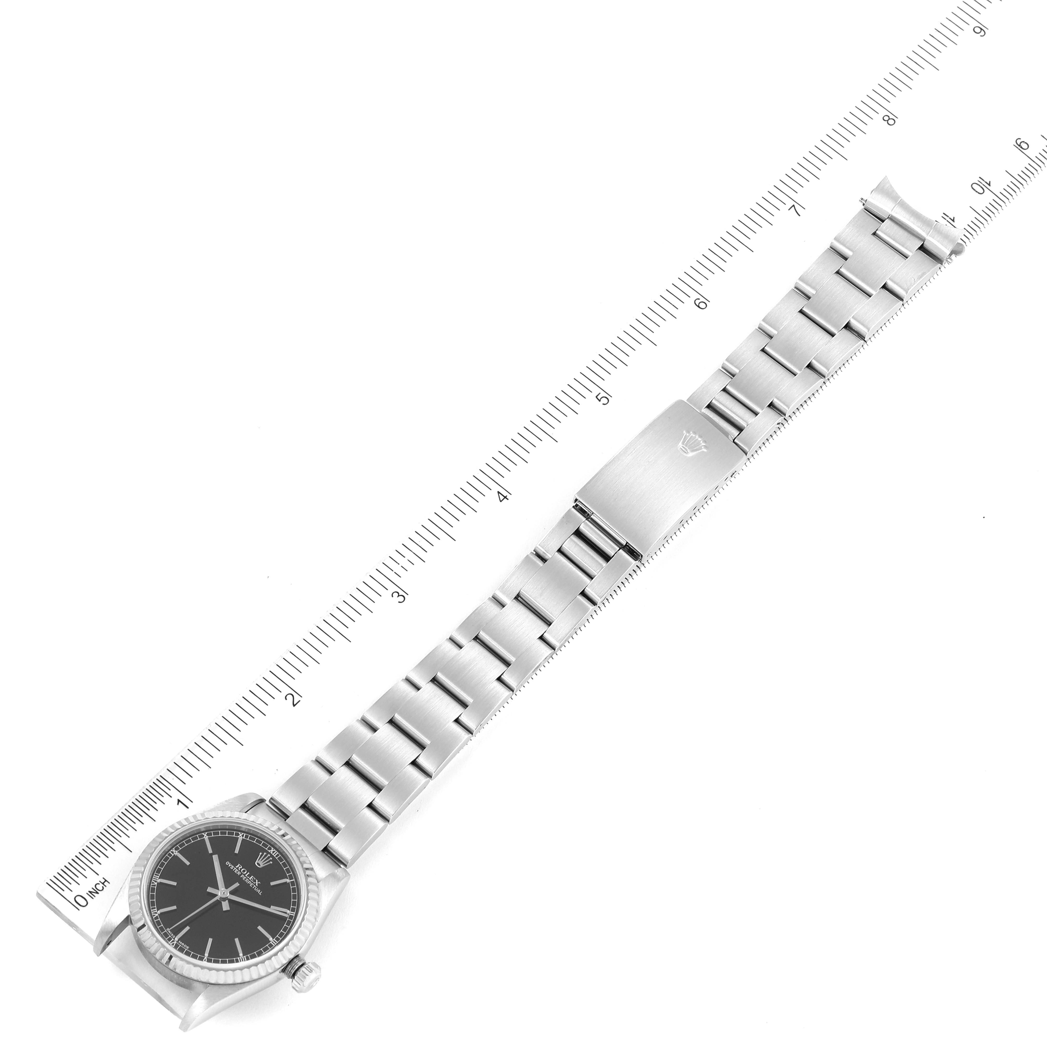 The image shows a top-down view of a mid-size Rolex watch, displaying its face, stainless steel bracelet, and clasp, alongside a ruler for scale.