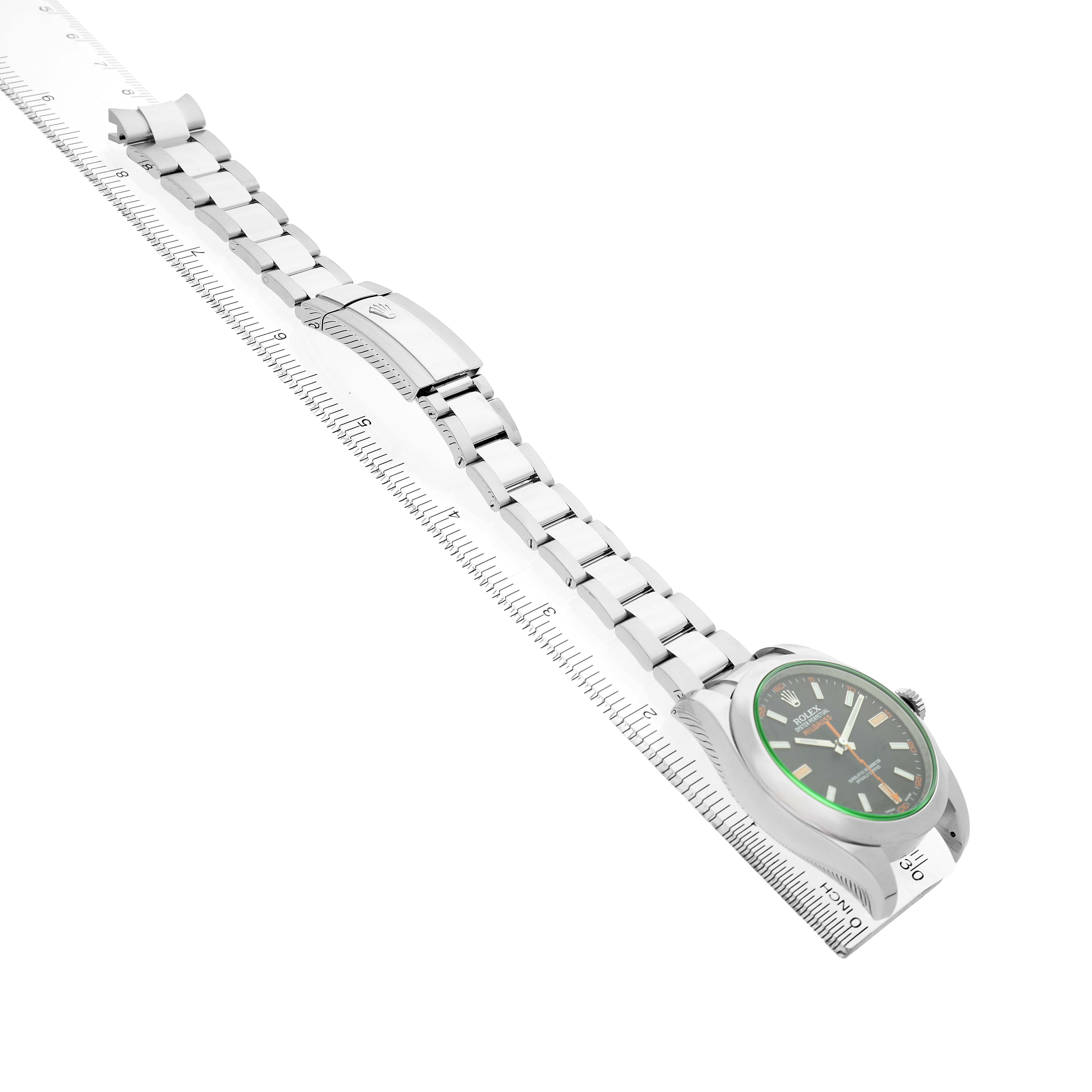 The Rolex Milgauss 116400GV Men's Stainless Steel Black Dial watch is shown partially side-on, highlighting the bracelet and clasp alongside a ruler.