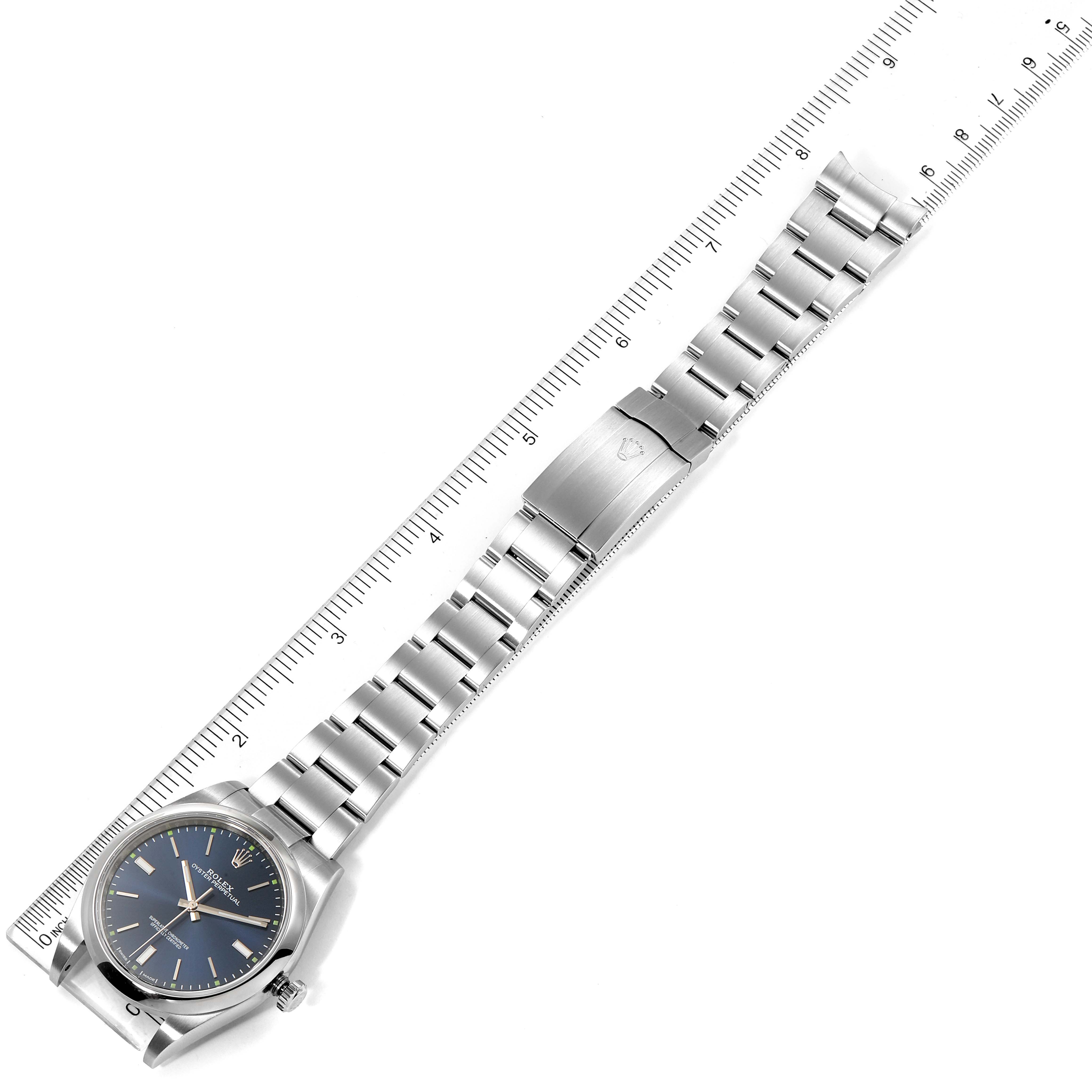 The image shows a top-down view of a Rolex Oyster Perpetual 114300 Men
s Stainless Steel Blue Dial 114300 Men
s Stainless Steel Blue Dial watch, including the face, case, and metal bracelet with a clasp.