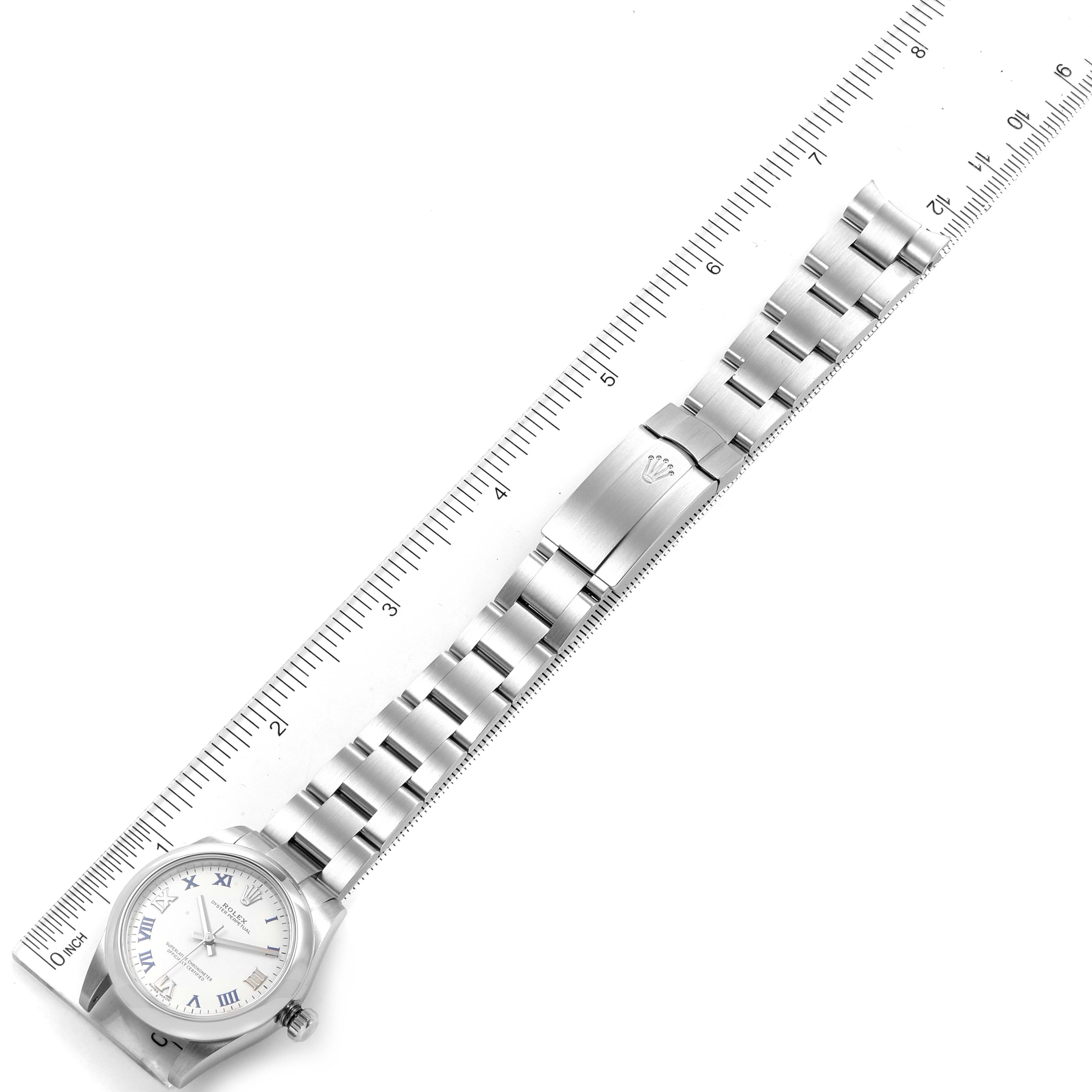 The image shows a Rolex Mid-Size 177200 Women
s Stainless Steel White Dial 177200 Women
s Stainless Steel White Dial model watch displayed diagonally with its band extended beside a ruler.
