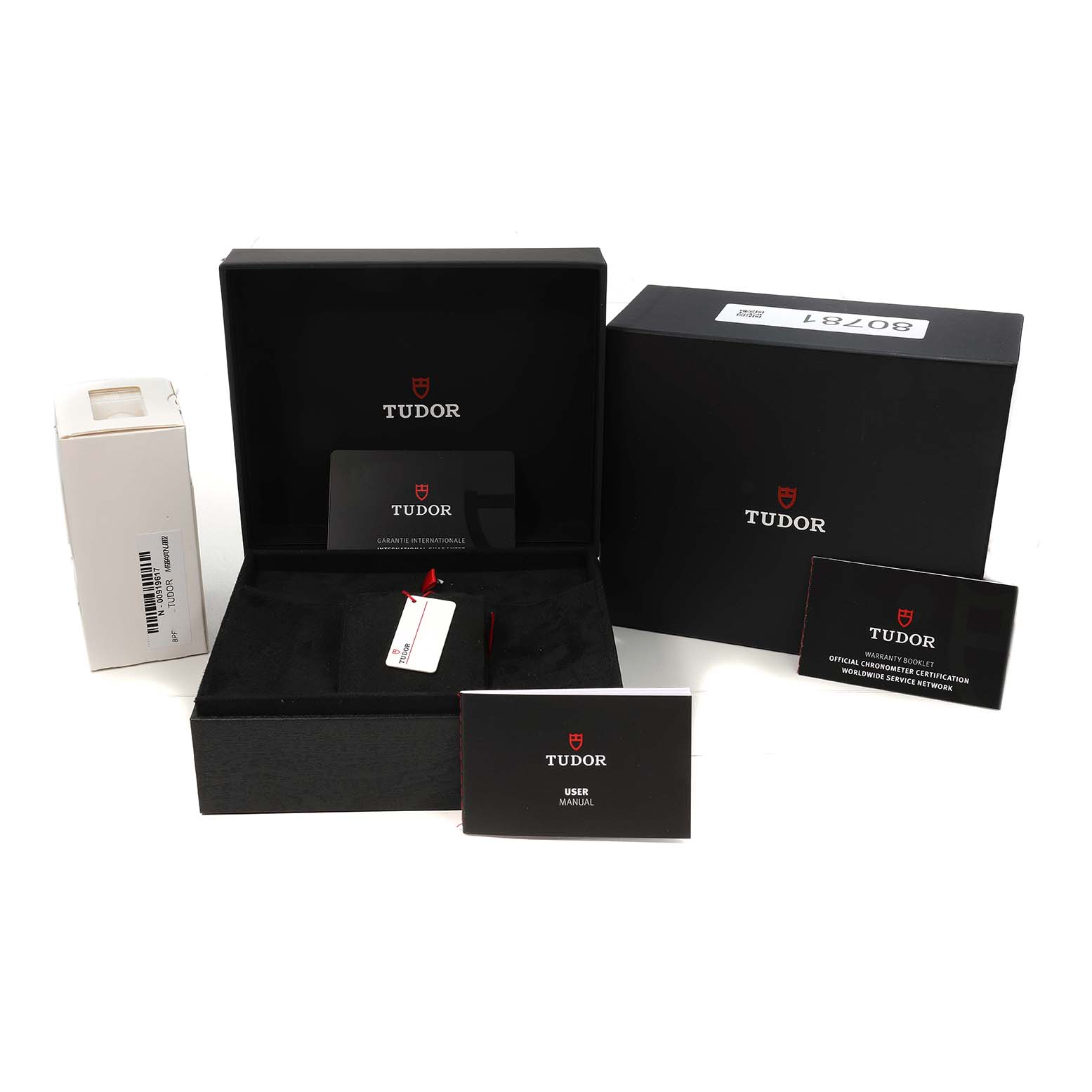 The image shows the Tudor Heritage Black Bay 7939A1A0NU Men's Stainless Steel Black Dial packaging, including boxes, a user manual, and certification cards, from a front angle.
