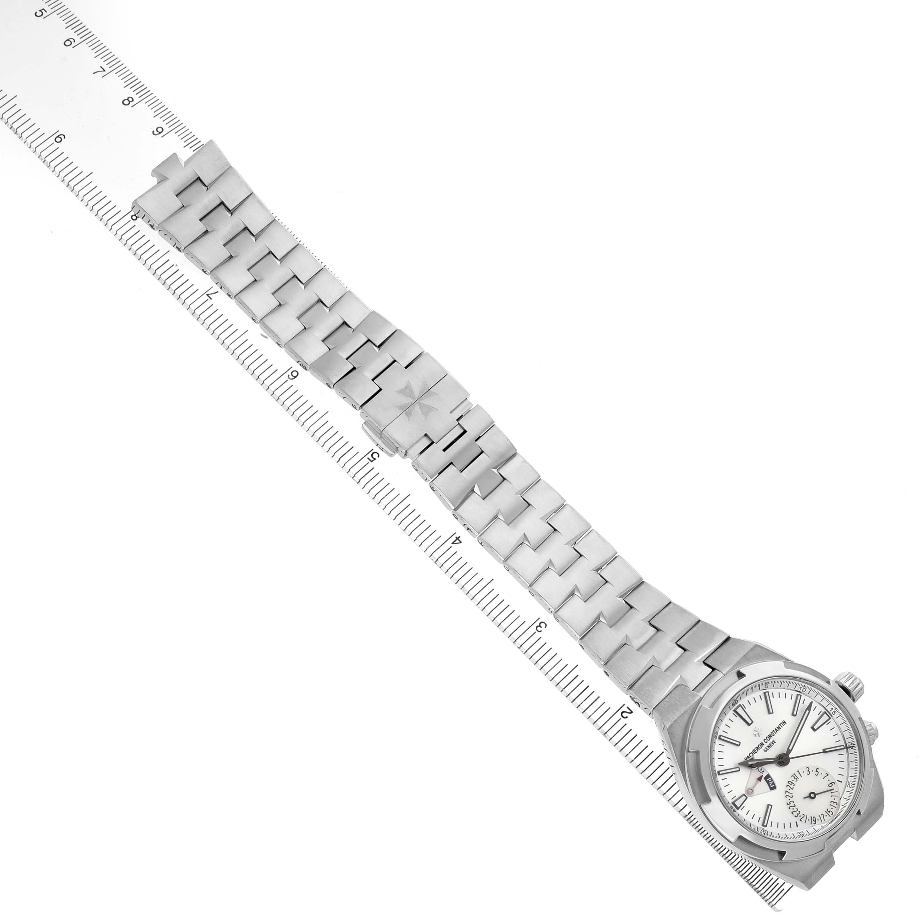 The Vacheron Constantin Overseas 7900V Men's Stainless Steel Silver Dial watch is shown from a top-down angle, displaying the full bracelet and face alongside a ruler for scale.