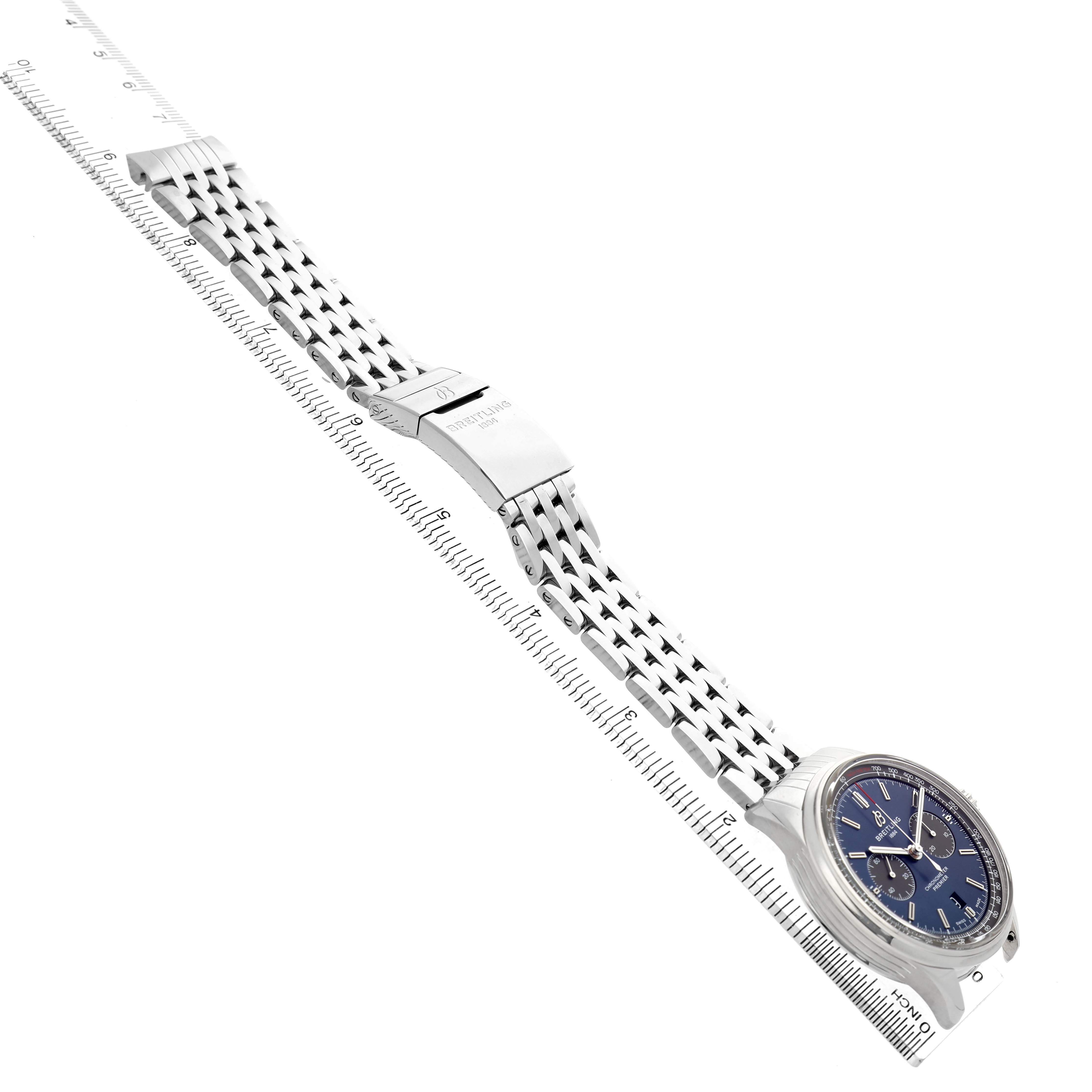 The Breitling Premier AB0118 Men's Stainless Steel Blue Dial watch is shown at an angle highlighting the face, stainless steel bracelet, and clasp alongside a ruler.