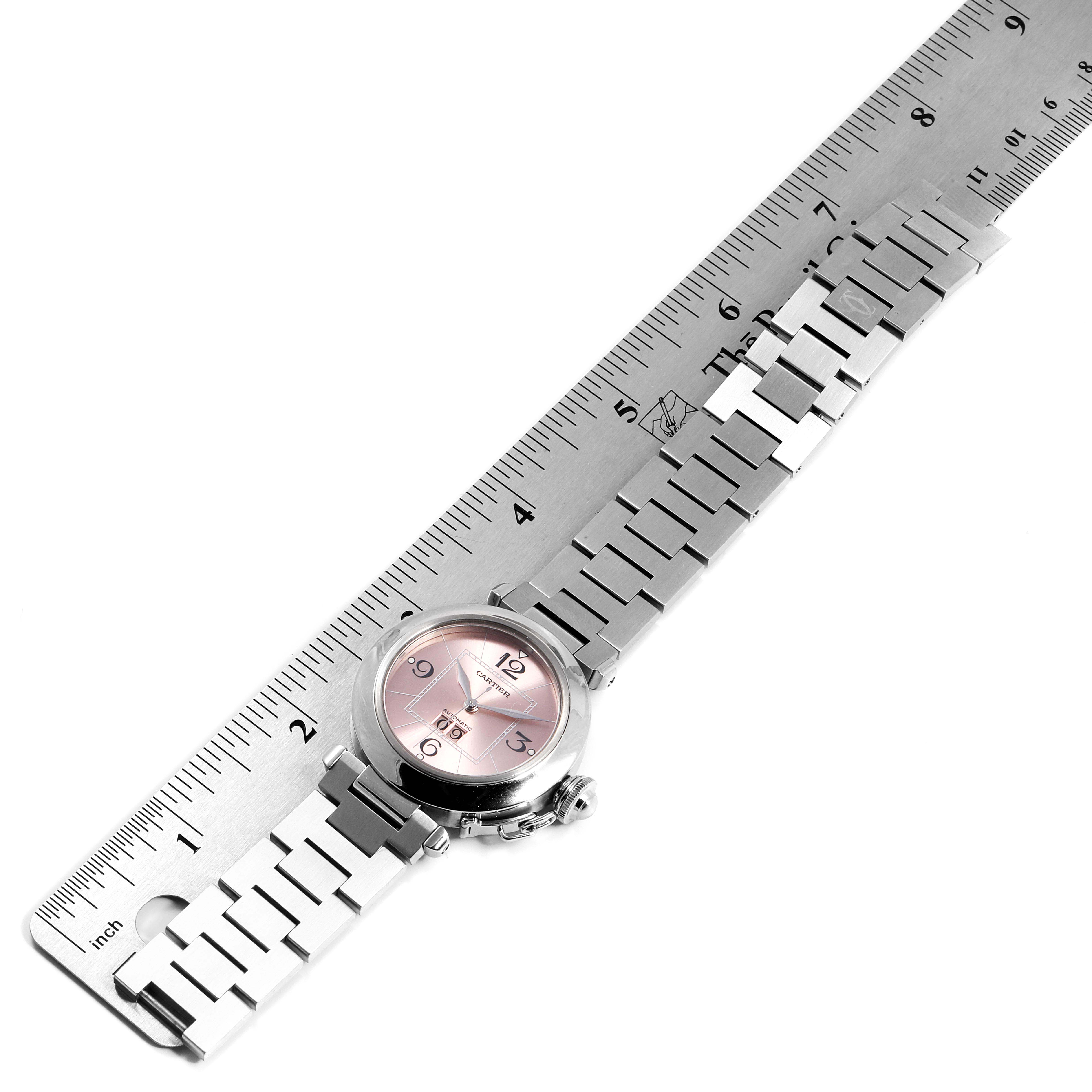 The image shows a Cartier Pasha W31058M7 Women
s Stainless Steel Pink Dial W31058M7 Women
s Stainless Steel Pink Dial watch laid flat with its stainless steel bracelet stretched next to a ruler.
