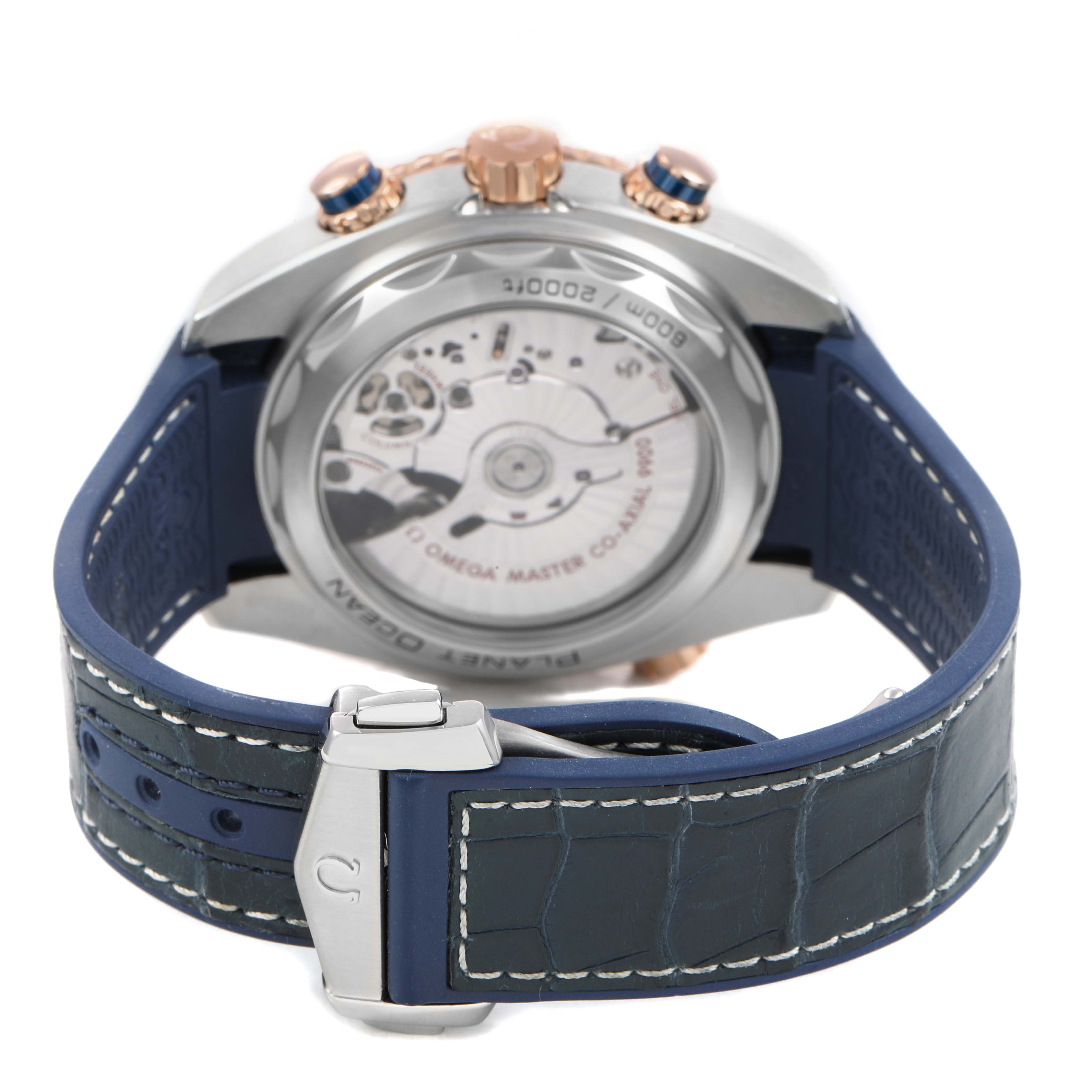 The image shows the back of the Omega Planet Ocean 215.23.46.51.03.001 Men's Steel and Gold (two tone) Blue Dial watch, highlighting the movement and the blue strap with clasp.