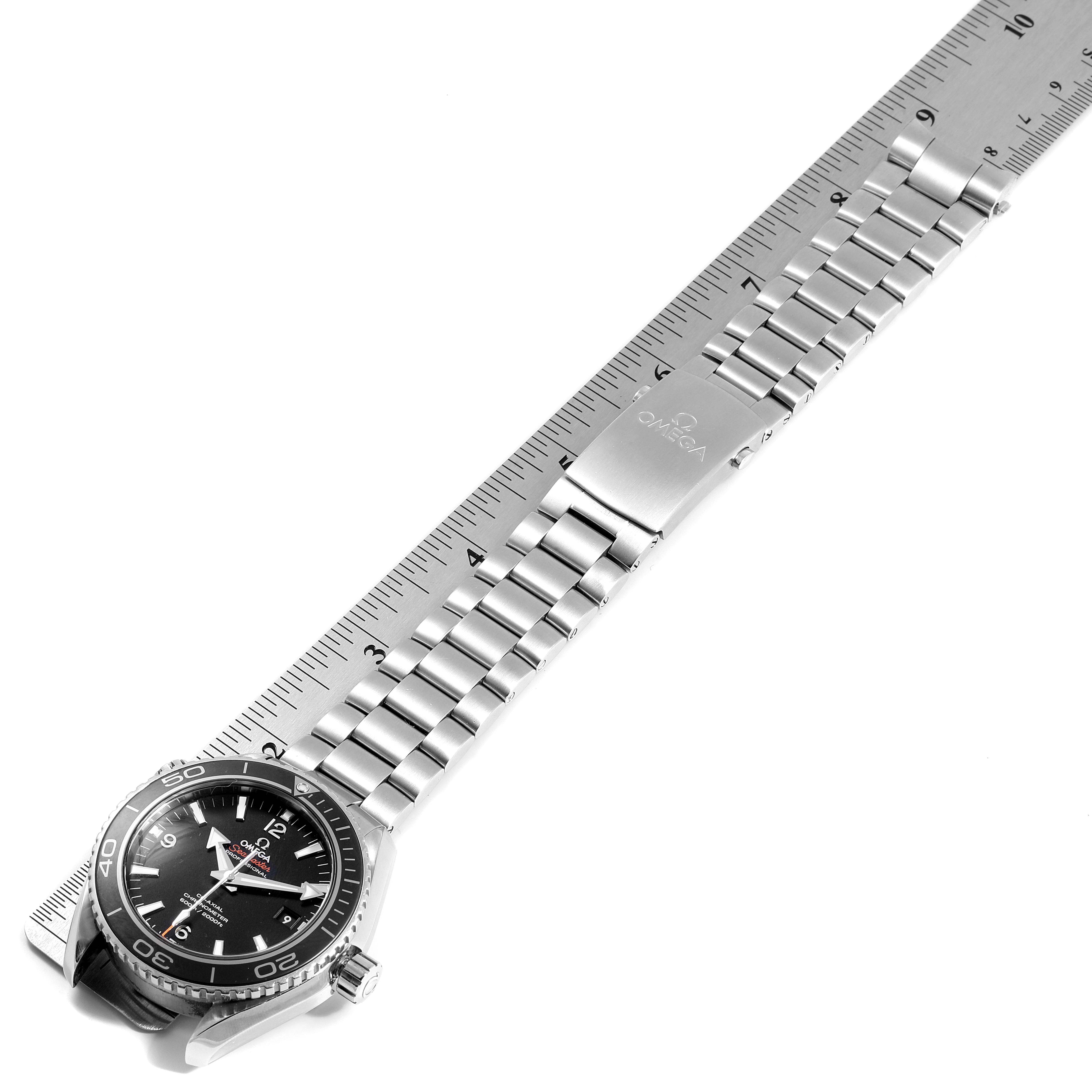 The image shows an Omega Seamaster 232.30.46.21.01.001 Men
s Stainless Steel Black Dial 232.30.46.21.01.001 Men
s Stainless Steel Black Dial watch at an oblique angle, with the face, bezel, stainless steel band, and clasp visible alongside a ruler.