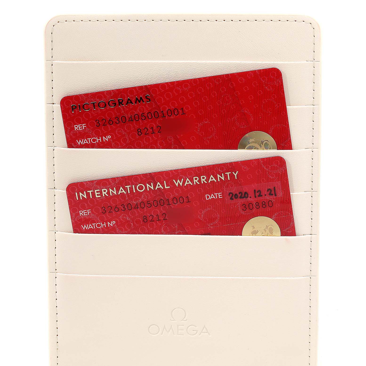 The image shows the warranty and pictogram cards for the Omega Speedmaster 326.30.40.50.01.001 Men
s Stainless Steel Black Dial 326.30.40.50.01.001 Men
s Stainless Steel Black Dial watch in a cream-colored cardholder.