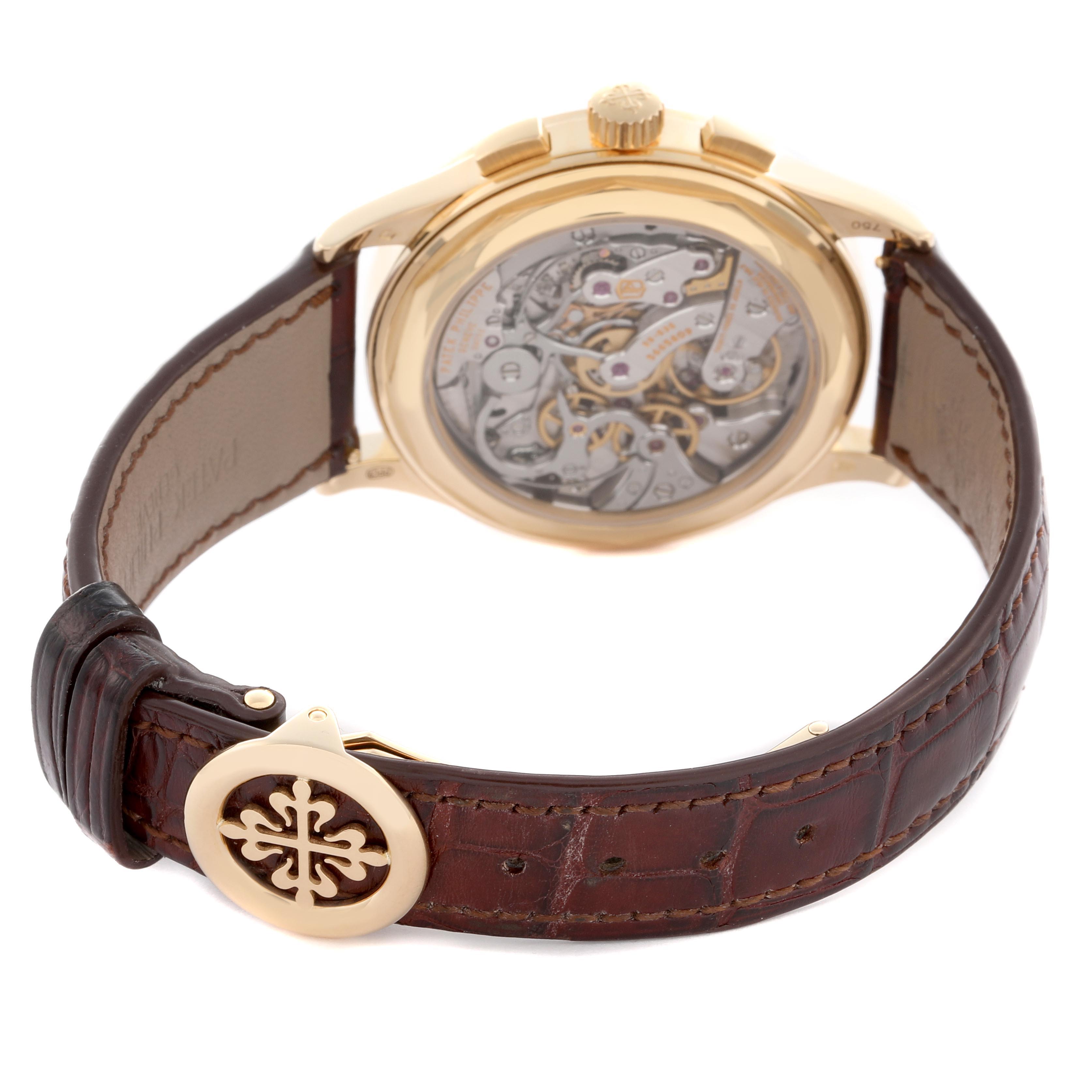 The Patek Philippe Complications 5170J Men
s Yellow Gold Silver Dial 5170J Men
s Yellow Gold Silver Dial watch is shown from the back angle, highlighting the movement and brown leather strap.