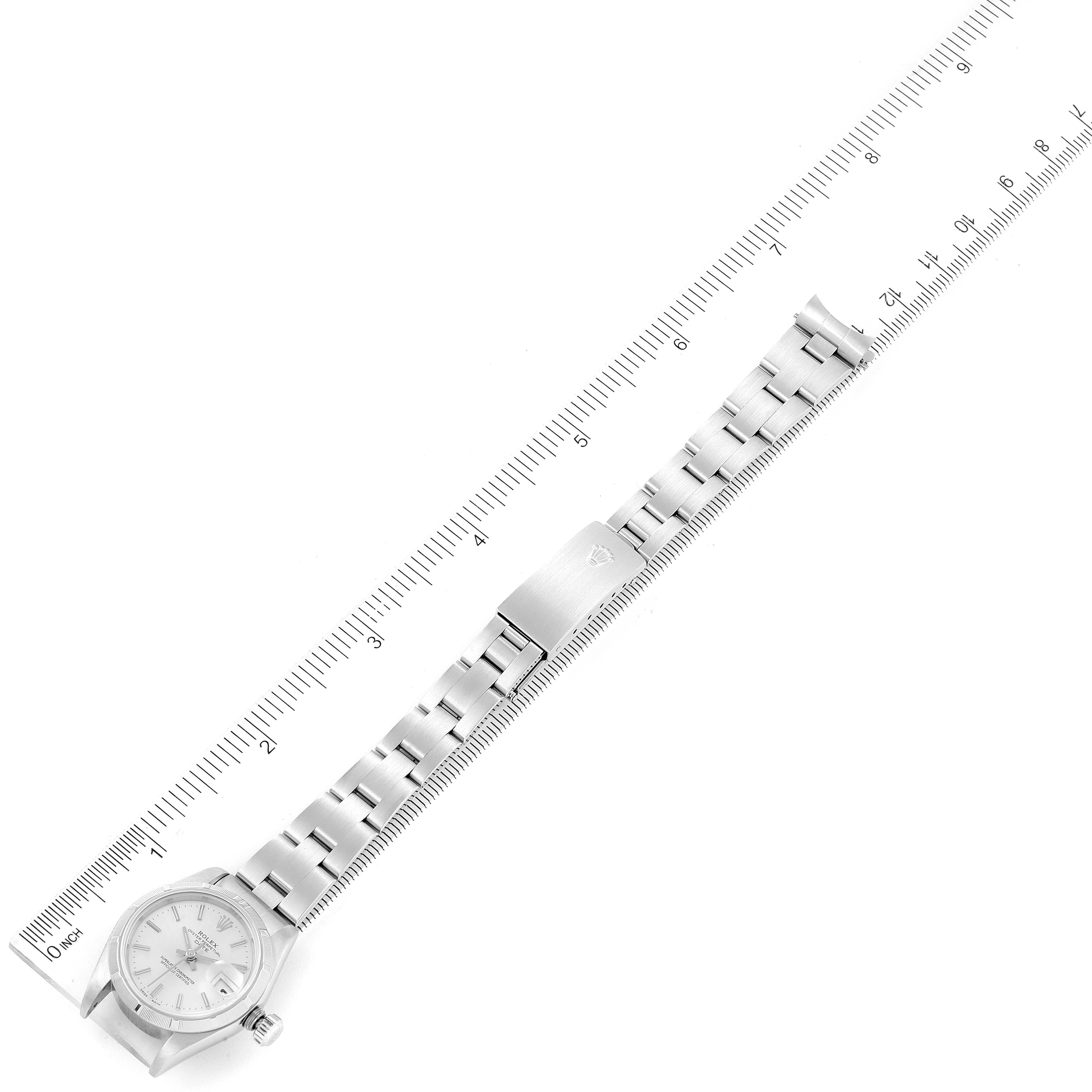 This image shows a top-down view of a Rolex Date 79190 Women's Stainless Steel Silver Dial 79190 Women's Stainless Steel Silver Dial model watch, including its dial, bracelet, and clasp alongside a ruler for measurement.