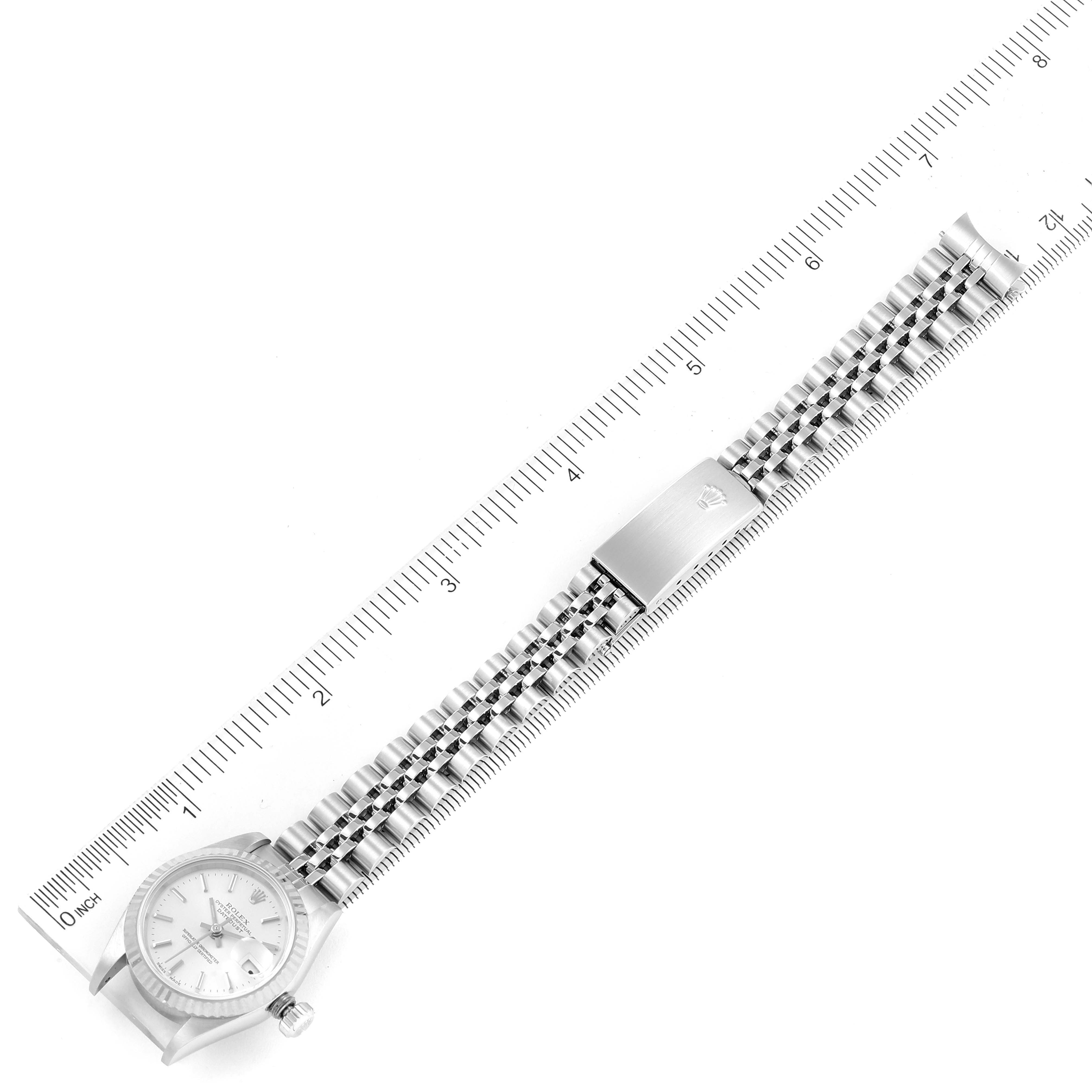This image displays a Rolex Datejust 79174 Women
s Stainless Steel Silver Dial 79174 Women
s Stainless Steel Silver Dial watch laid flat with a ruler, revealing the watch face, crown, and entire bracelet.