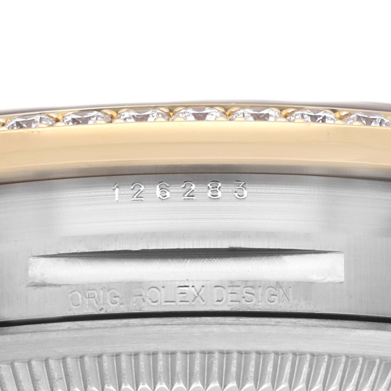 The image shows a side view of a Rolex Datejust 126283 Men
s Steel and Gold (two tone) Silver Dial 126283 Men
s Steel and Gold (two tone) Silver Dial case, focusing on the bezel with diamonds, serial number, and design engraving.