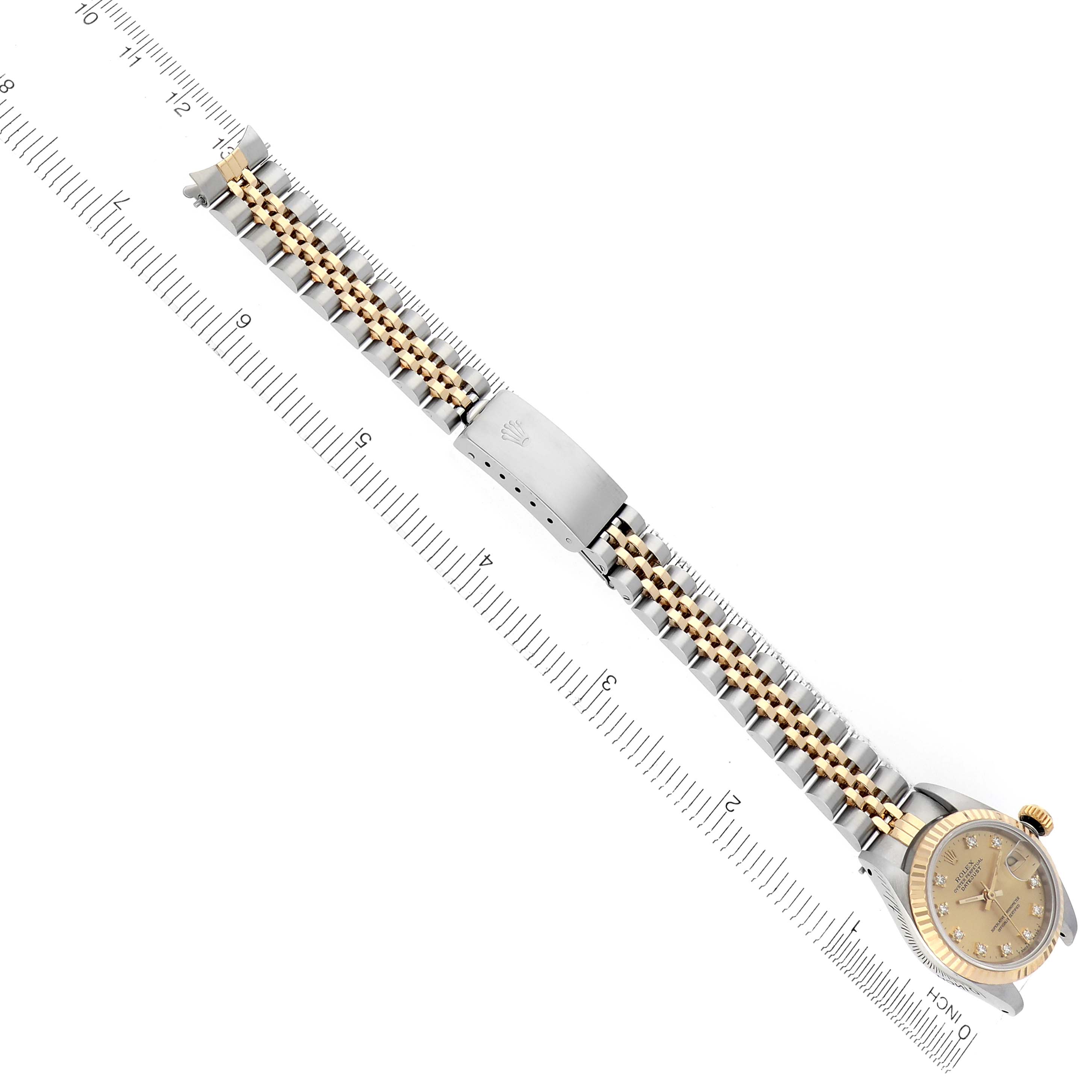 The Rolex Datejust 69173 Women's Steel and Gold (two tone) Champagne Dial 69173 Women's Steel and Gold (two tone) Champagne Dial watch is shown from an angled side view, featuring the band, clasp, and face next to a measuring ruler.
