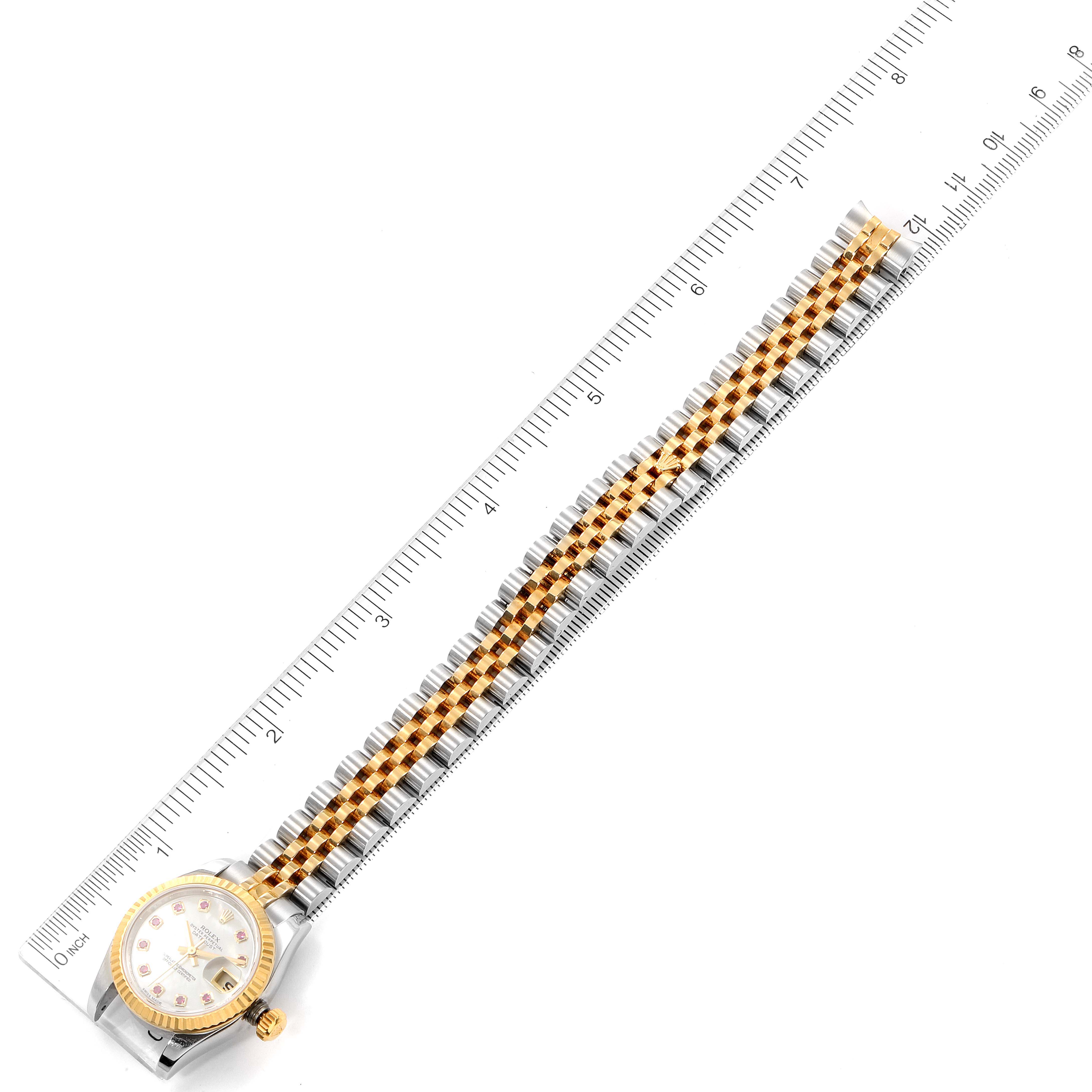 The Rolex Datejust 179173 Women's Steel and Gold (two tone) Mother of Pearl Dial 179173 Women's Steel and Gold (two tone) Mother of Pearl Dial watch is shown from an aerial view, with the entire length of the band and dial visible alongside a ruler for scale.