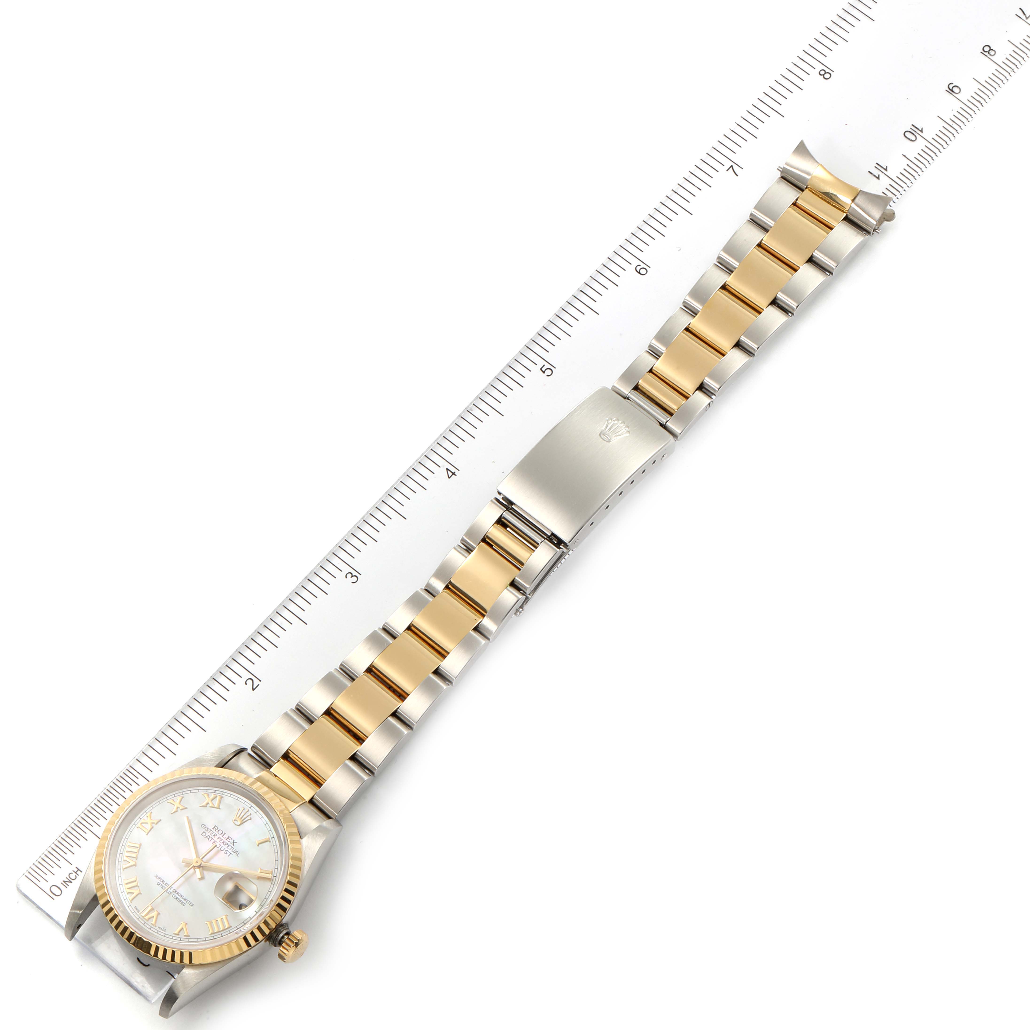 This image shows a top-down view of the Rolex Datejust 16233 Men's Steel and Gold (two tone) Mother of Pearl Dial 16233 Men's Steel and Gold (two tone) Mother of Pearl Dial watch with a two-tone metal bracelet and ruler for scale.