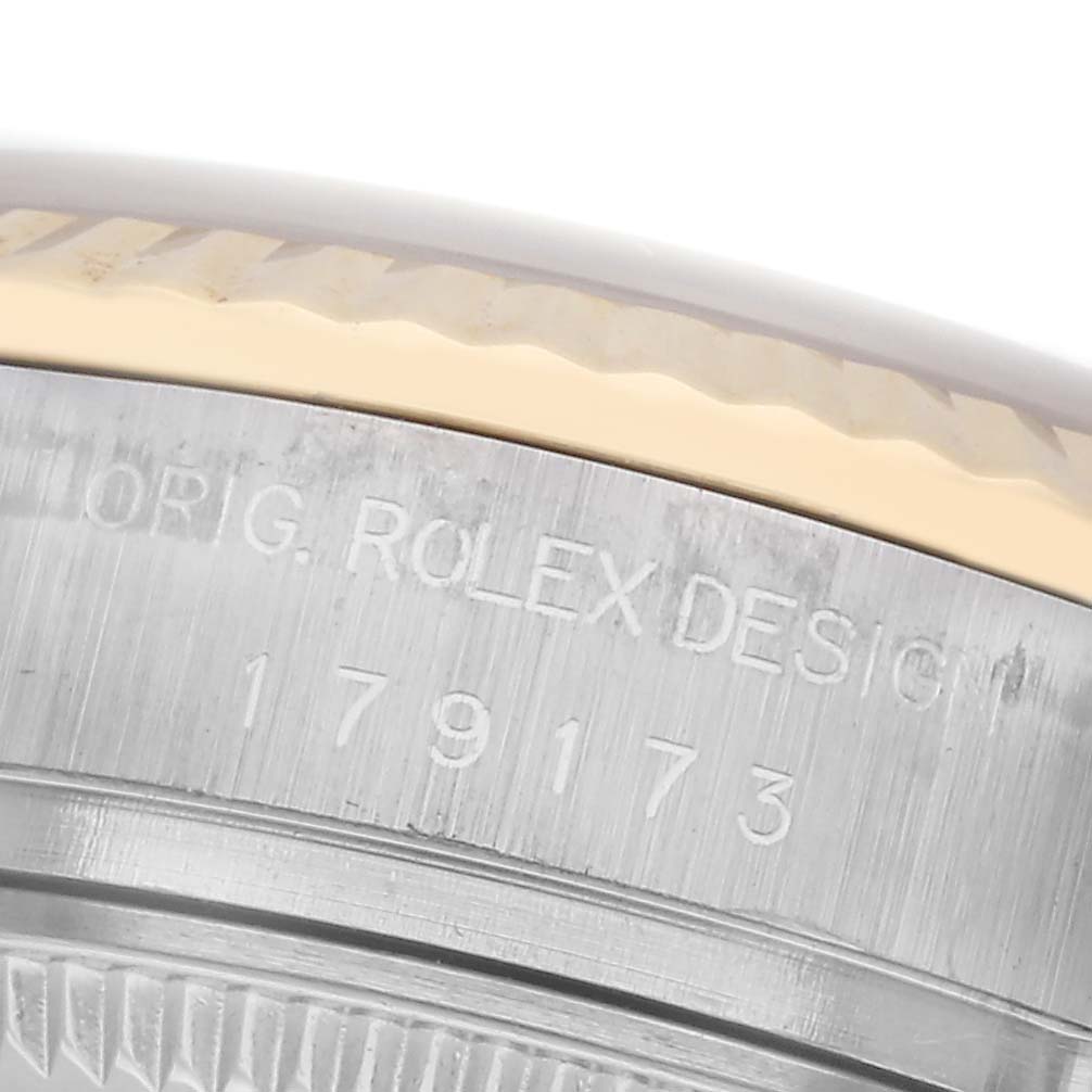 The image shows a close-up of a Rolex Datejust 179173 Women's Steel and Gold (two tone) White Dial 179173 Women's Steel and Gold (two tone) White Dial model's side, highlighting the textured bezel and engraved design number.