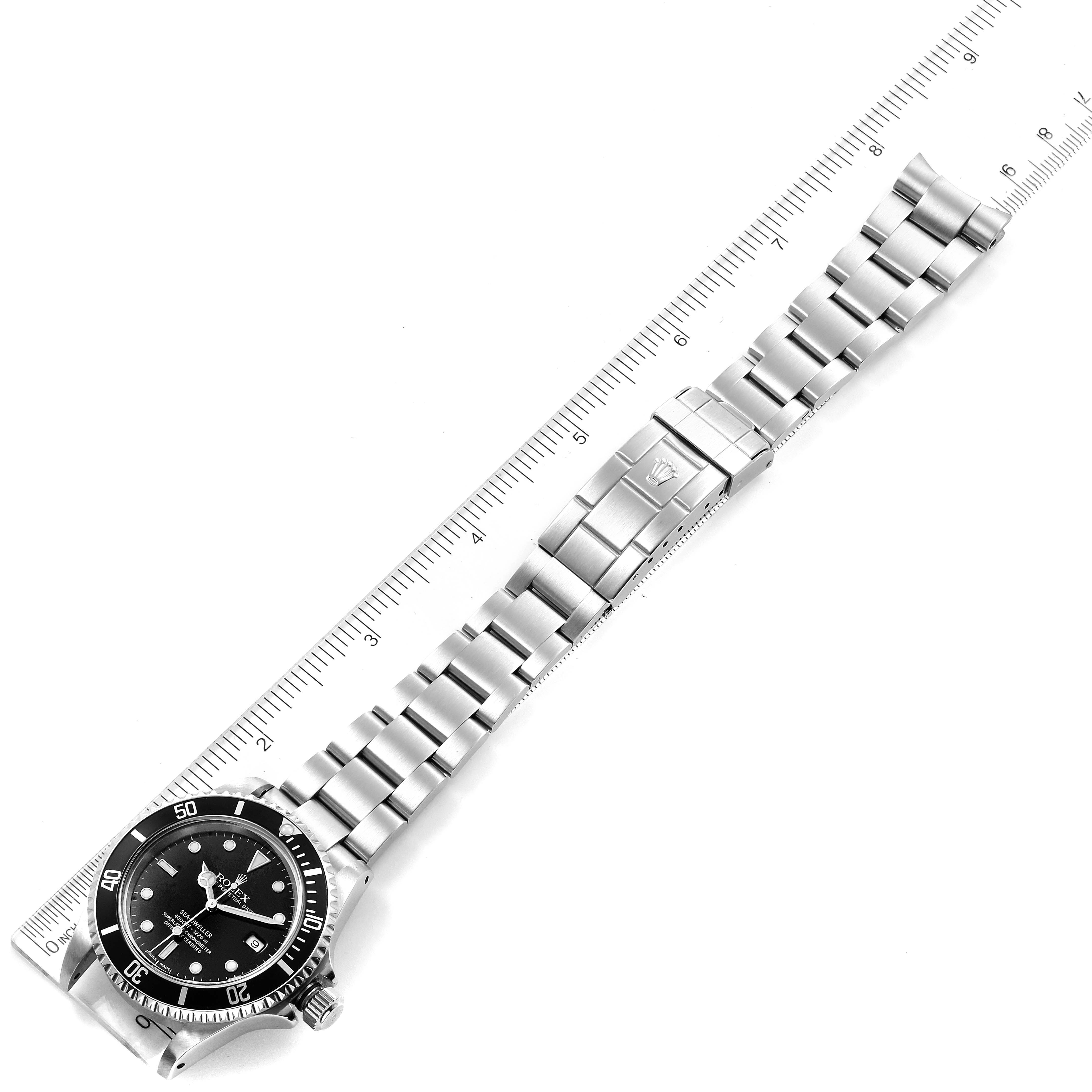 The image shows a top-down view of a Rolex Sea-Dweller 16600 Men
s Stainless Steel Black Dial 16600 Men
s Stainless Steel Black Dial watch, including its face, bracelet, and clasp, placed next to a ruler.  