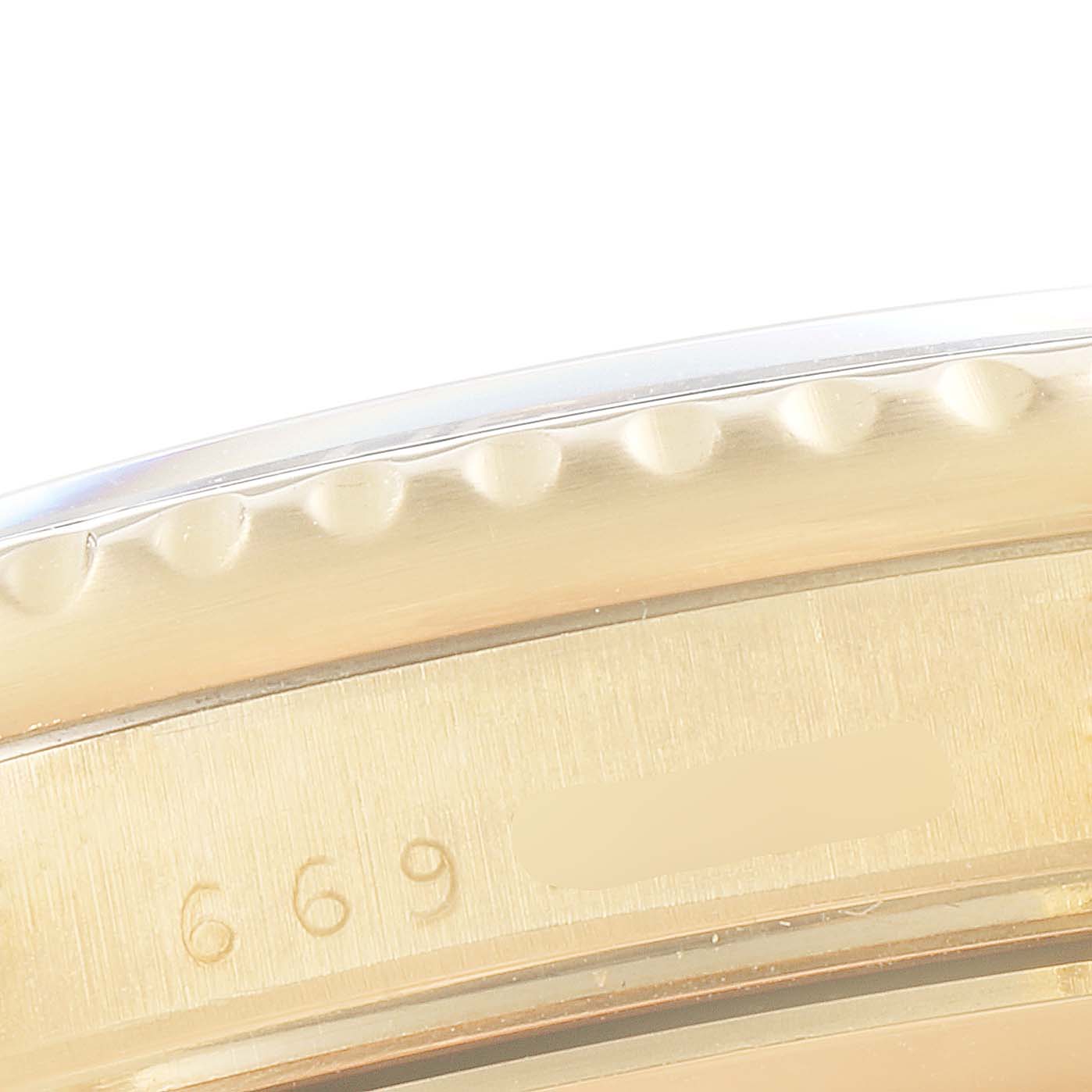 This image shows a close-up of the bezel and the case, including part of the engravings, of a Rolex Submariner 16808 Men's Yellow Gold Black Dial 16808 Men's Yellow Gold Black Dial watch.