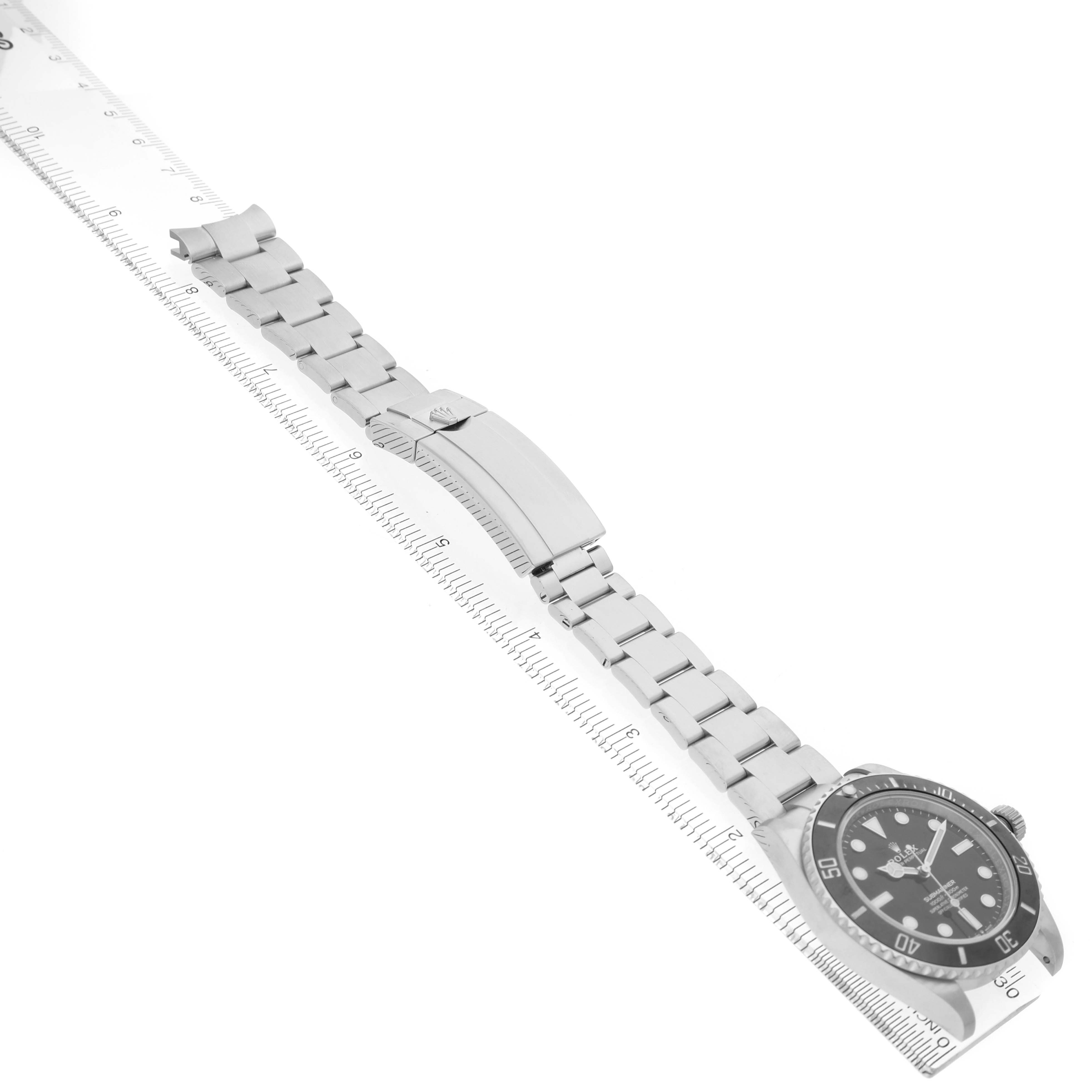 The image shows a side view of a Rolex Submariner M124060-0001 Men's Stainless Steel Black Dial watch, highlighting its bracelet and clasp, aligned with a ruler.