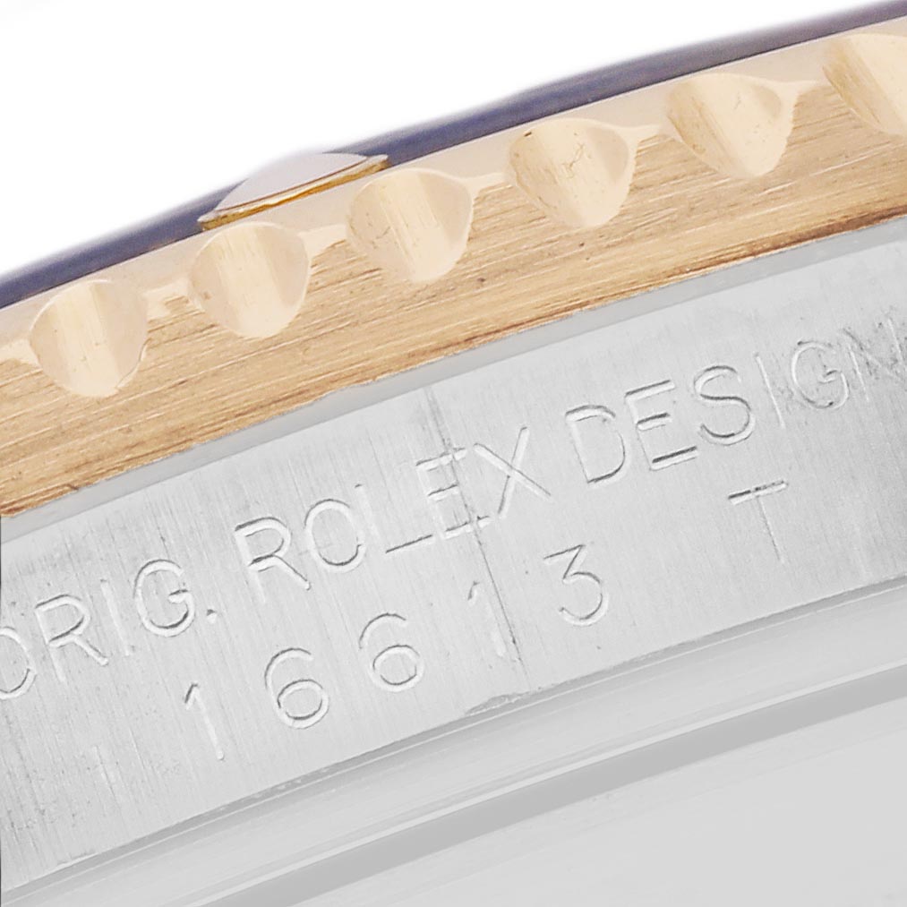 The image shows the side angle of a Rolex Submariner 16613 Men
s Steel and Gold (two tone) Silver Dial 16613 Men
s Steel and Gold (two tone) Silver Dial, focusing on the engraved case and bezel edge.