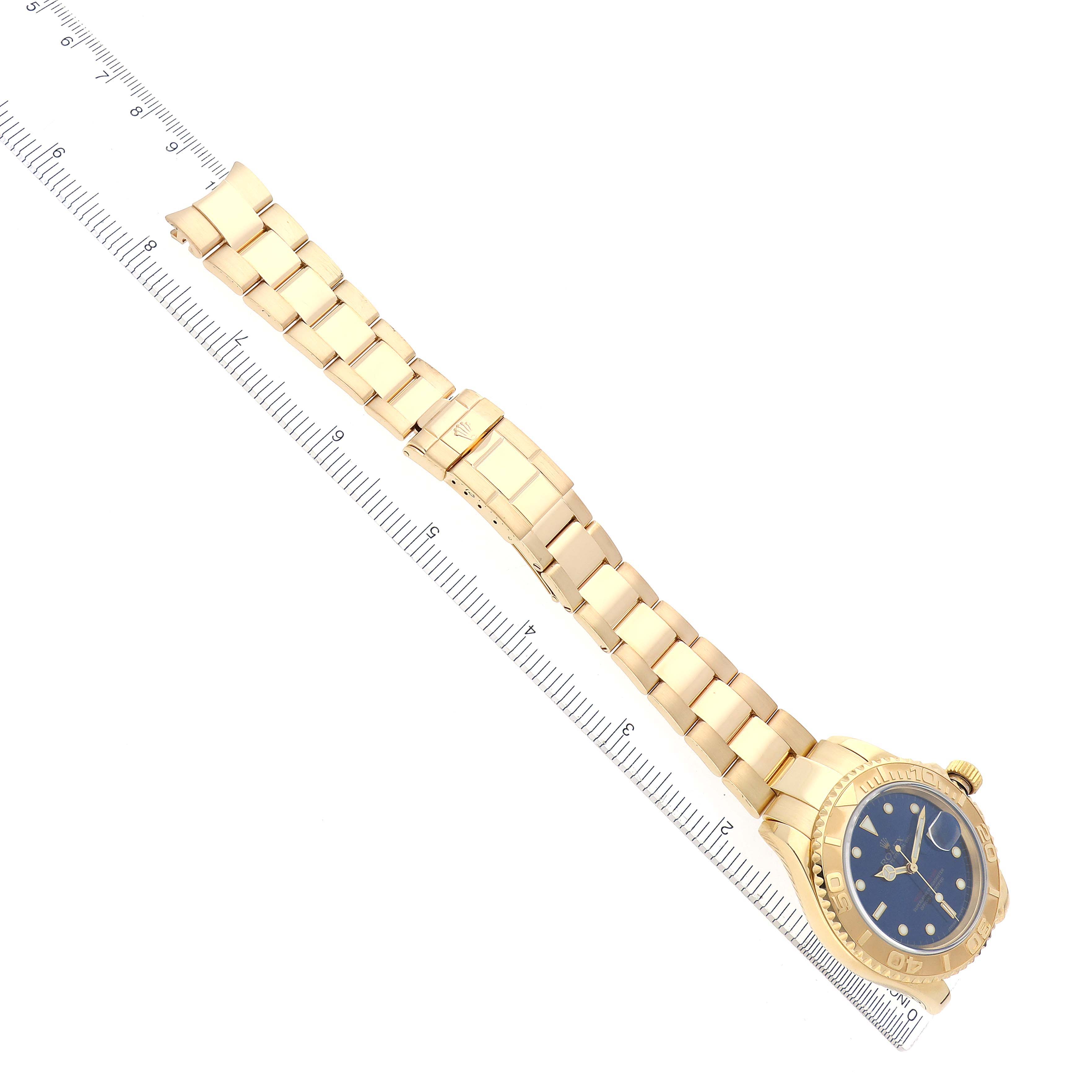 The Rolex Yacht-Master 16628 Men
s Yellow Gold Blue Dial 16628 Men
s Yellow Gold Blue Dial watch is shown from a top-down angle, displaying the dial, bezel, bracelet, and clasp aligned with a ruler.