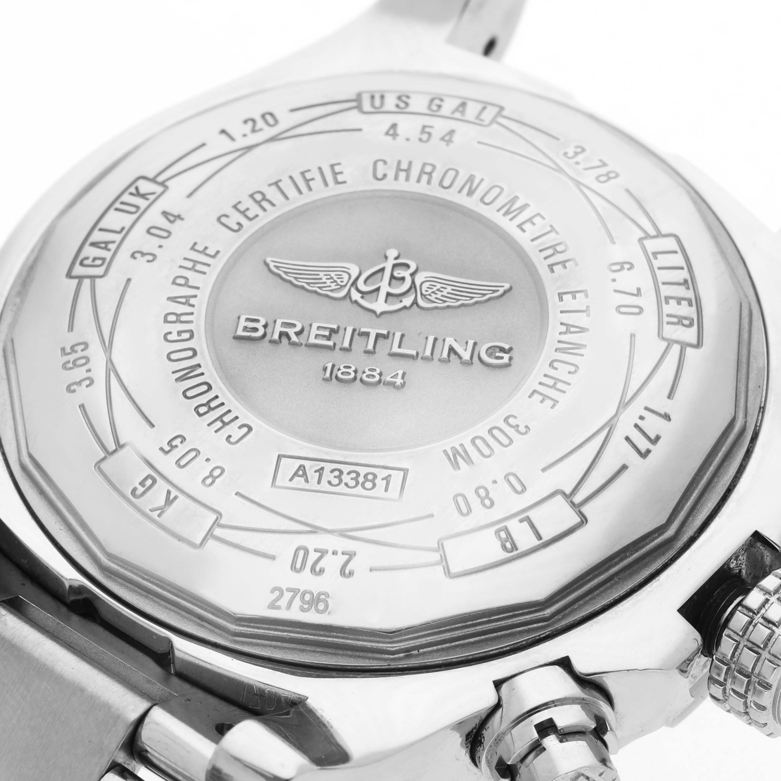 The image shows the back of a Breitling Avenger A13381 Men
s Stainless Steel Black Dial A13381 Men
s Stainless Steel Black Dial watch, featuring engravings and a partial view of the bracelet and crown.