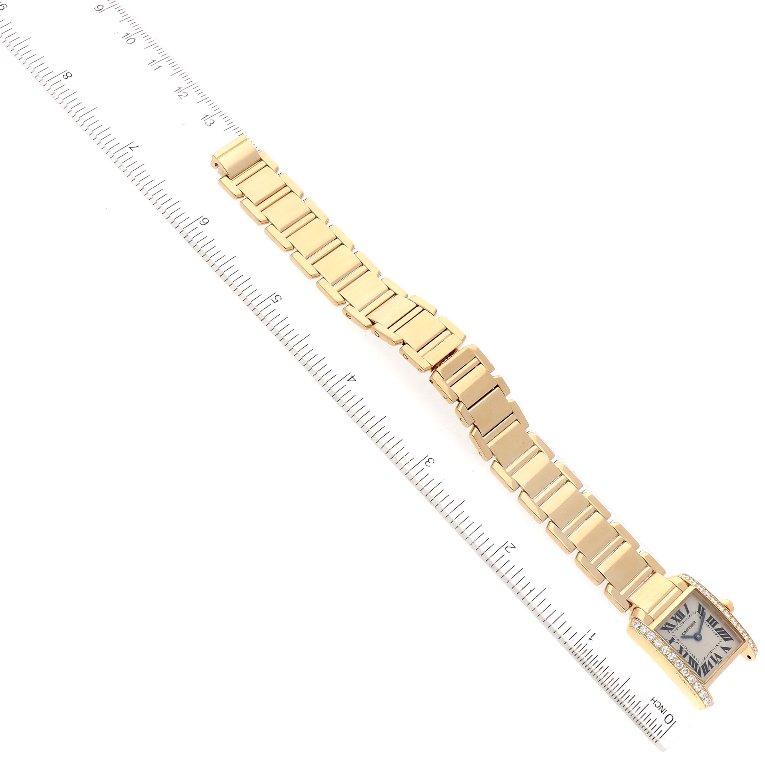 The image shows an overhead view of a Cartier Tank Francaise WE1001R8 Women
s Yellow Gold Silver Dial WE1001R8 Women
s Yellow Gold Silver Dial watch with a gold bracelet and ruler for scale.