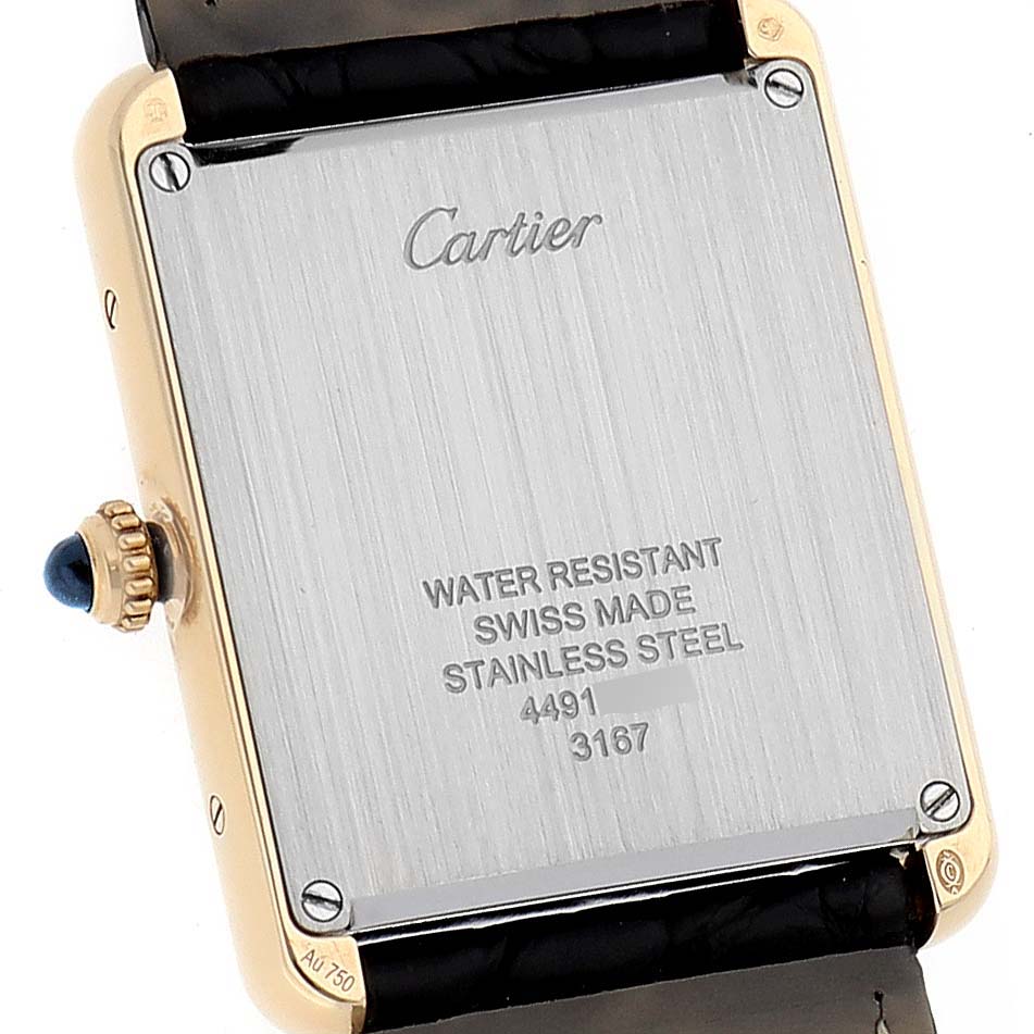 The image shows the back case of a Cartier Tank Solo W5200004 Men's Yellow Gold Silver Dial W5200004 Men's Yellow Gold Silver Dial watch, featuring engravings and the crown with a blue cabochon.