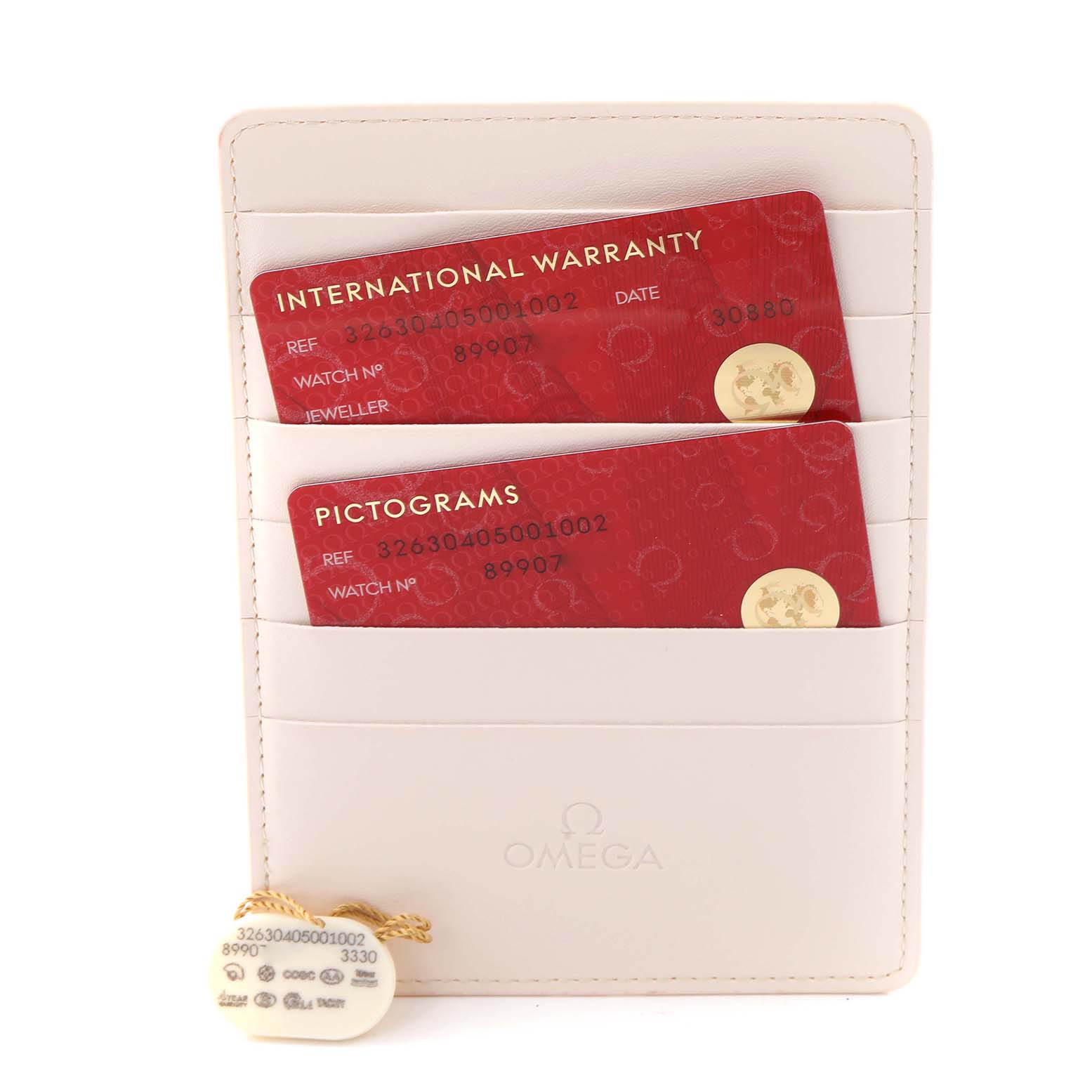 The image shows the international warranty and pictogram cards for the Omega Speedmaster 326.30.40.50.01.002 Men
s Stainless Steel Black Dial 326.30.40.50.01.002 Men
s Stainless Steel Black Dial, along with a cream cardholder and a tag.